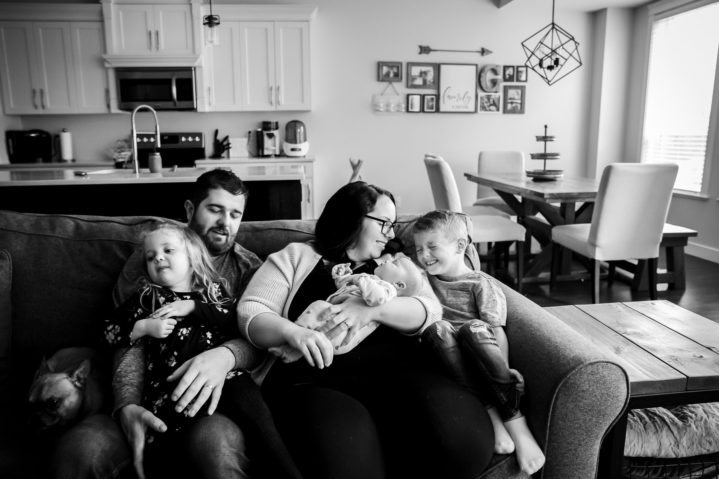 family and newborn sitting on couch snuggling together love newborn baby