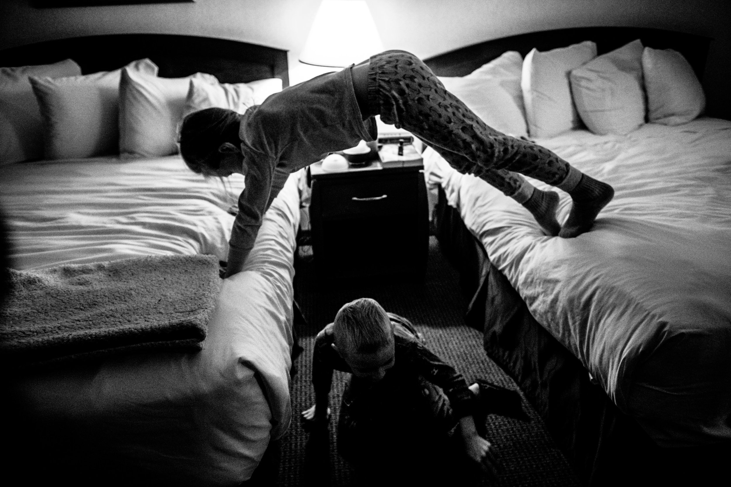 kids in hotel room playing on beds making a bridge with one child crawling under