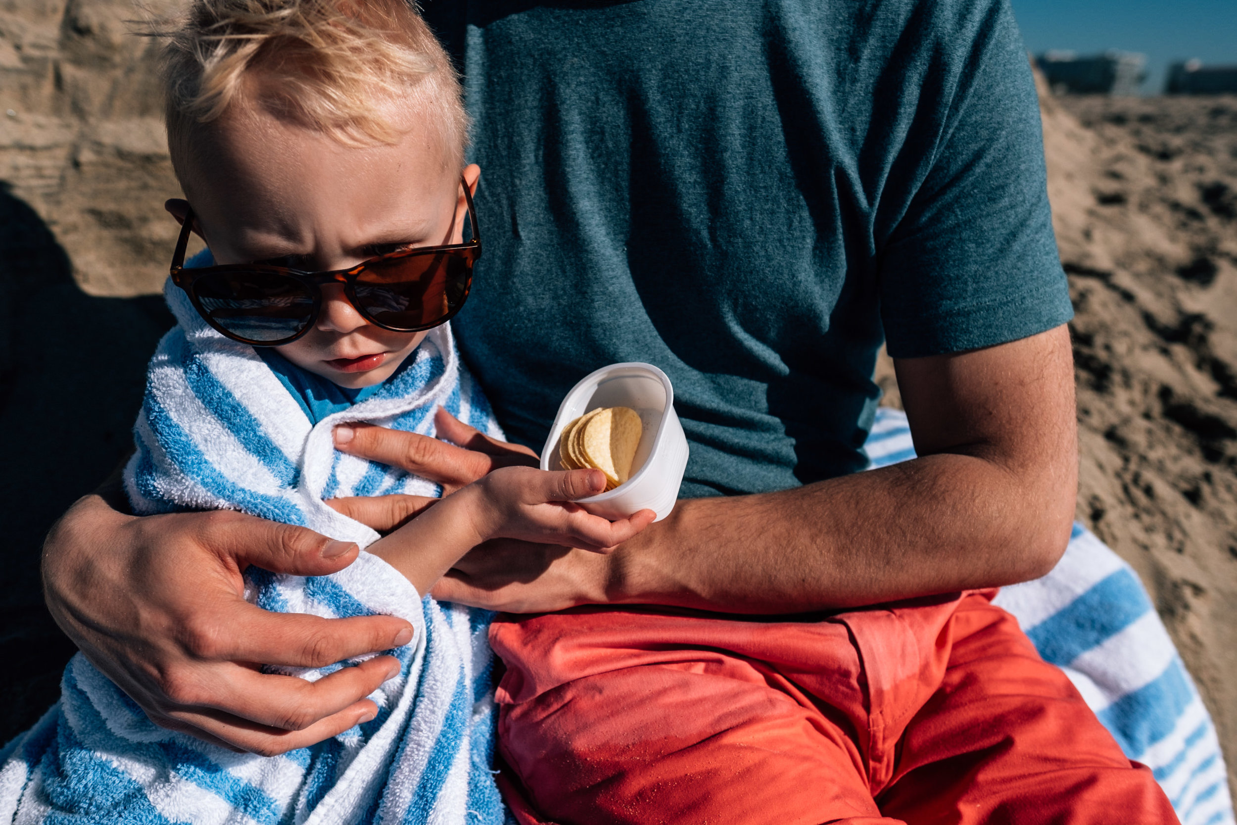 upset child boy being snuggled by his dad eating pringles
