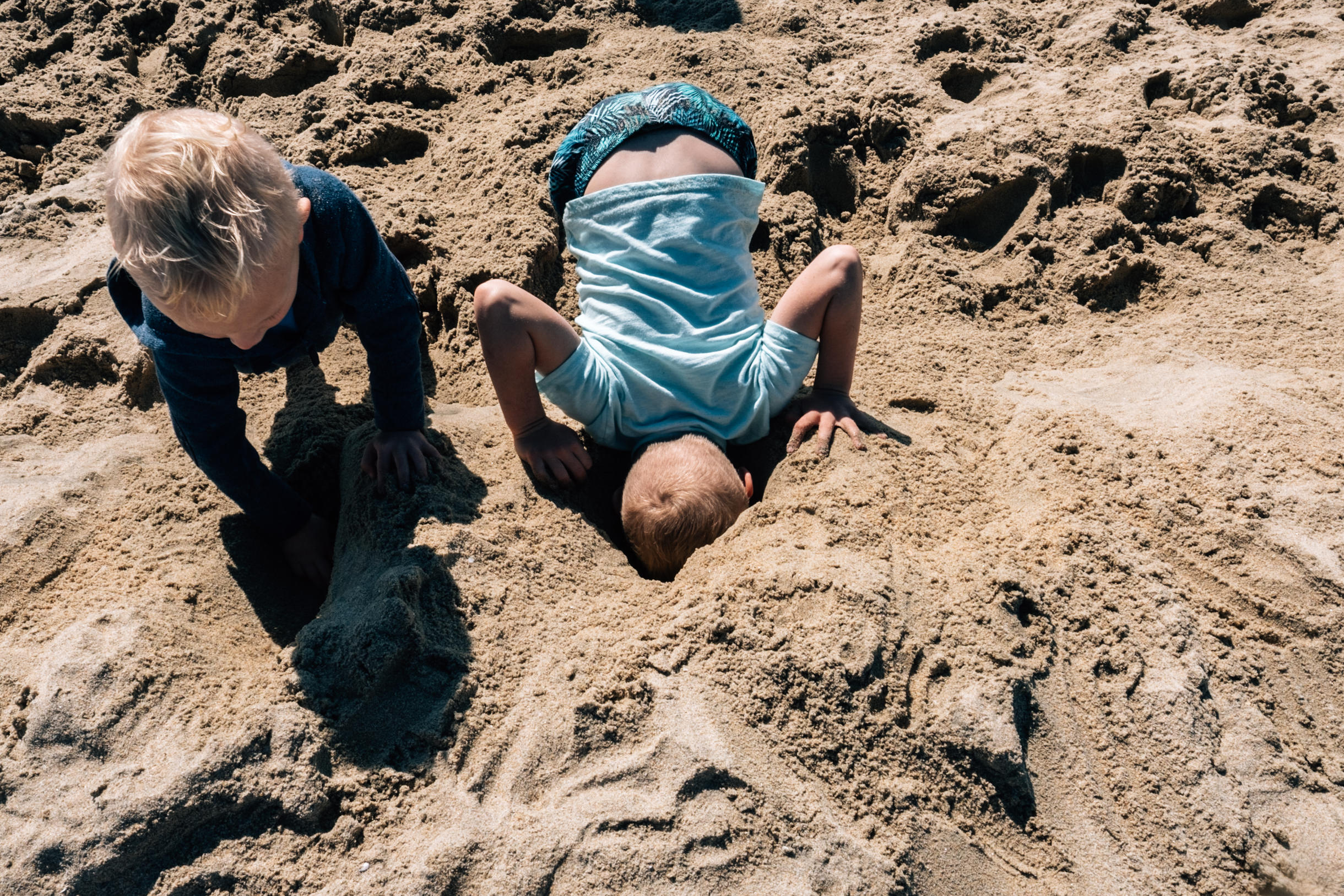 boy sticking his head in the sand at the beach vancouver photographer
