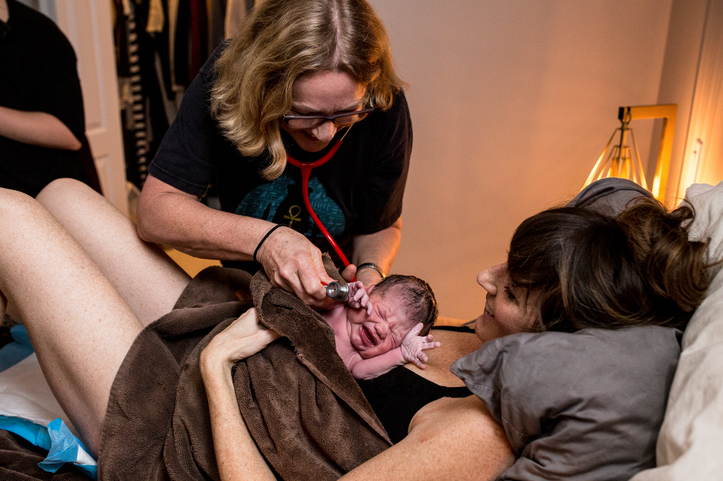 midwife checking over freshly birthed baby