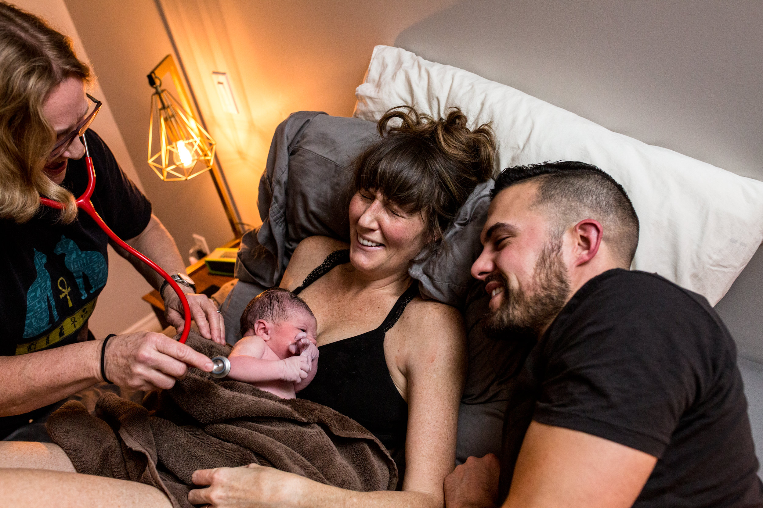 mom and dad laughing after birth with midwife
