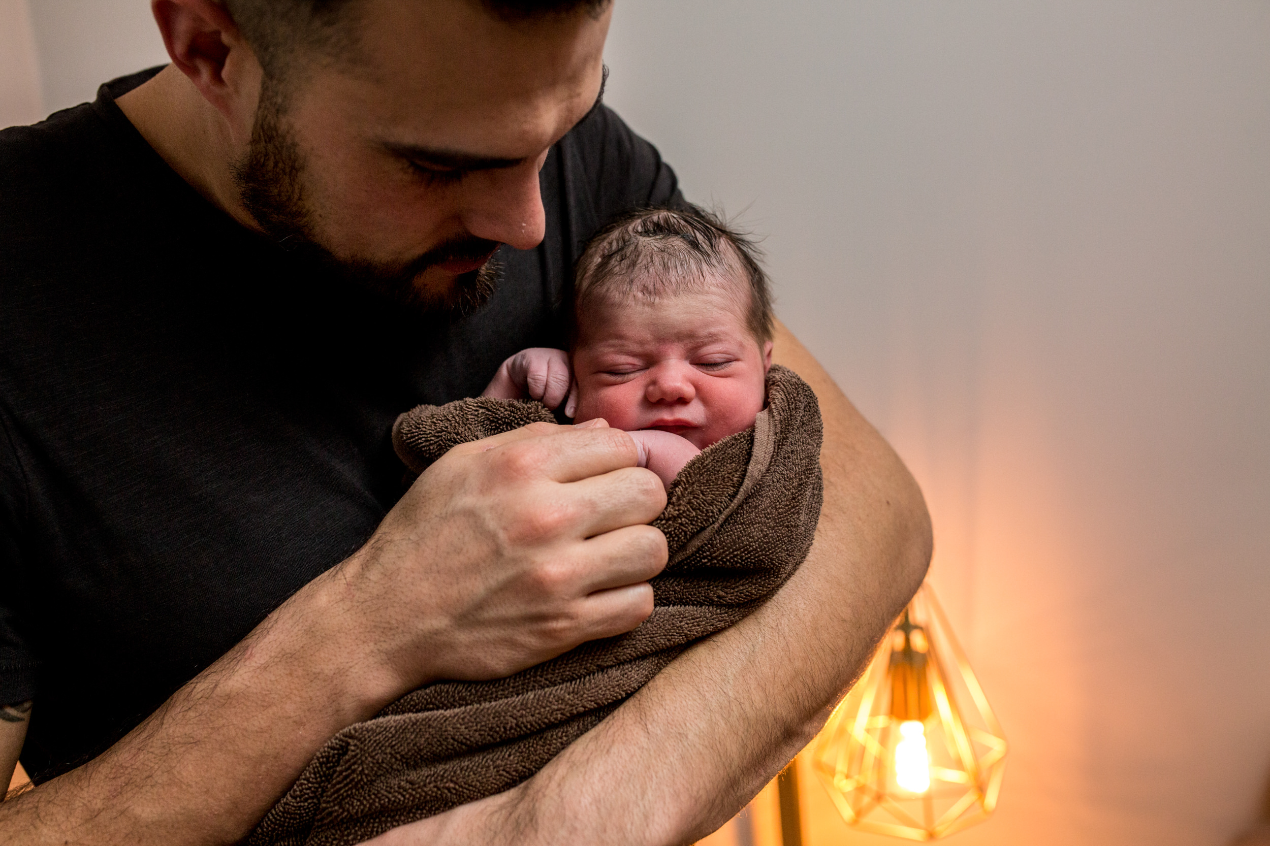 dad standing holding baby in a brown towel