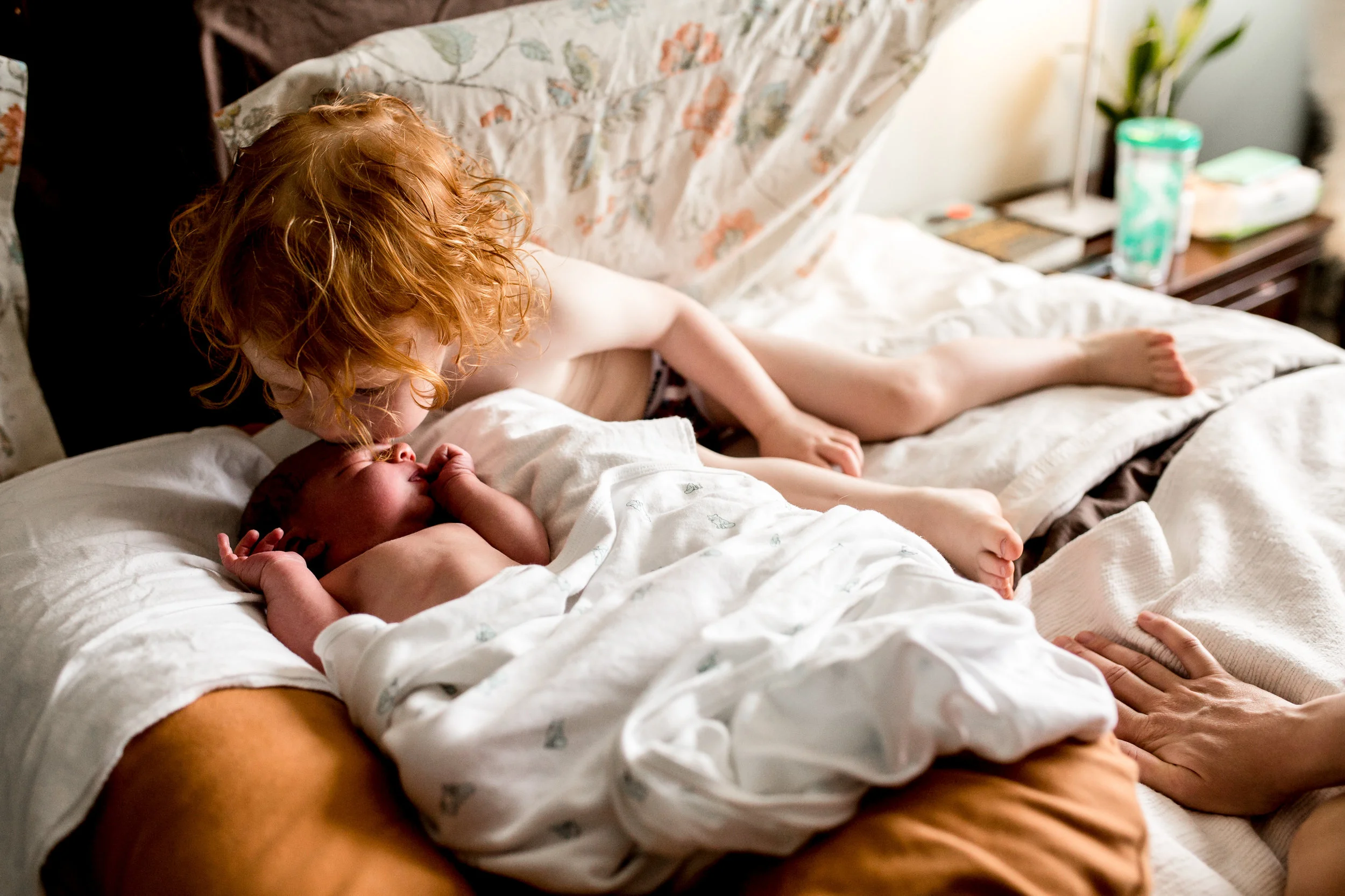 little boy kissing his newborn baby brother