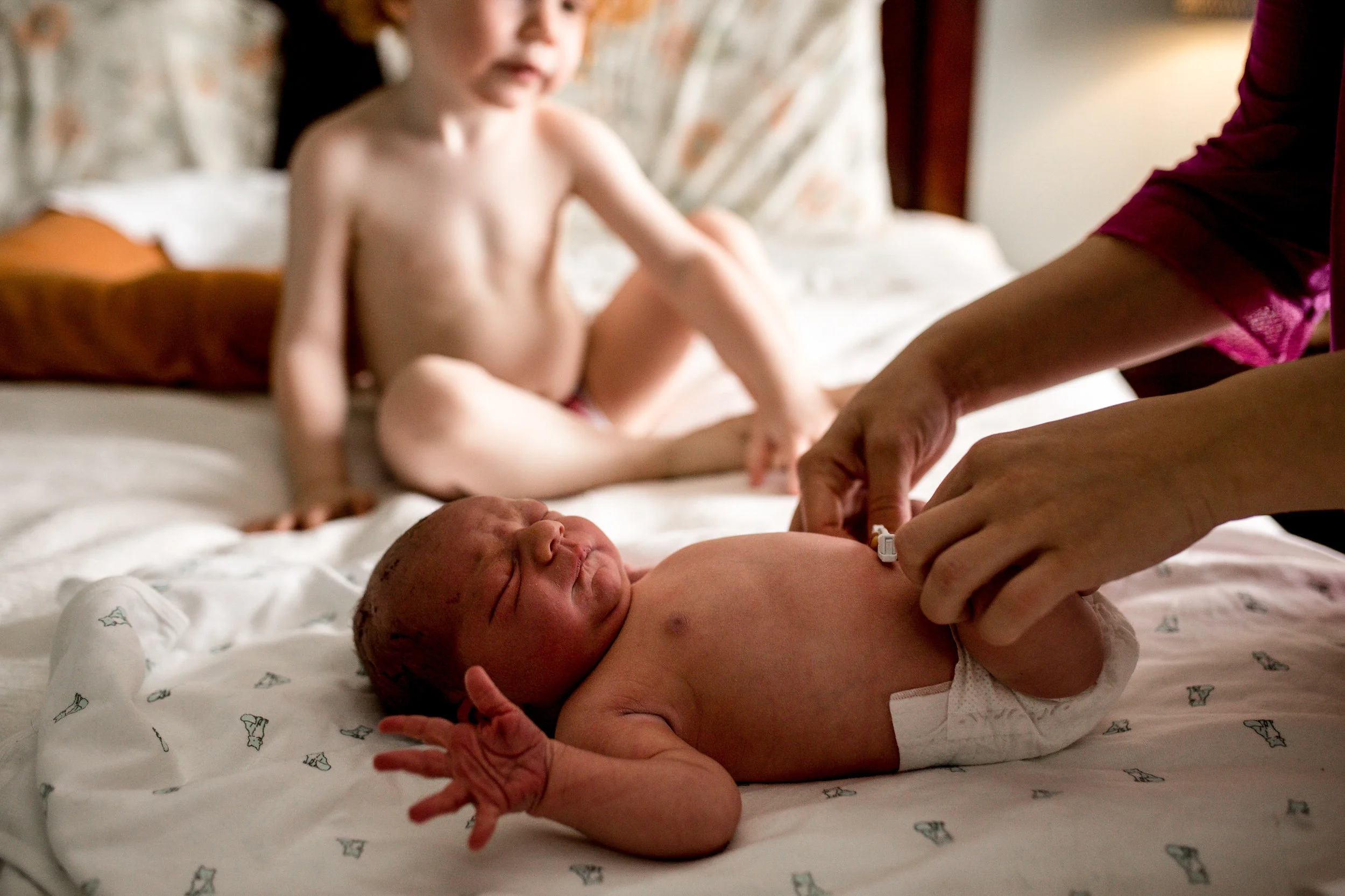 woman-changing-baby-diaper-toddler-watching.jpg