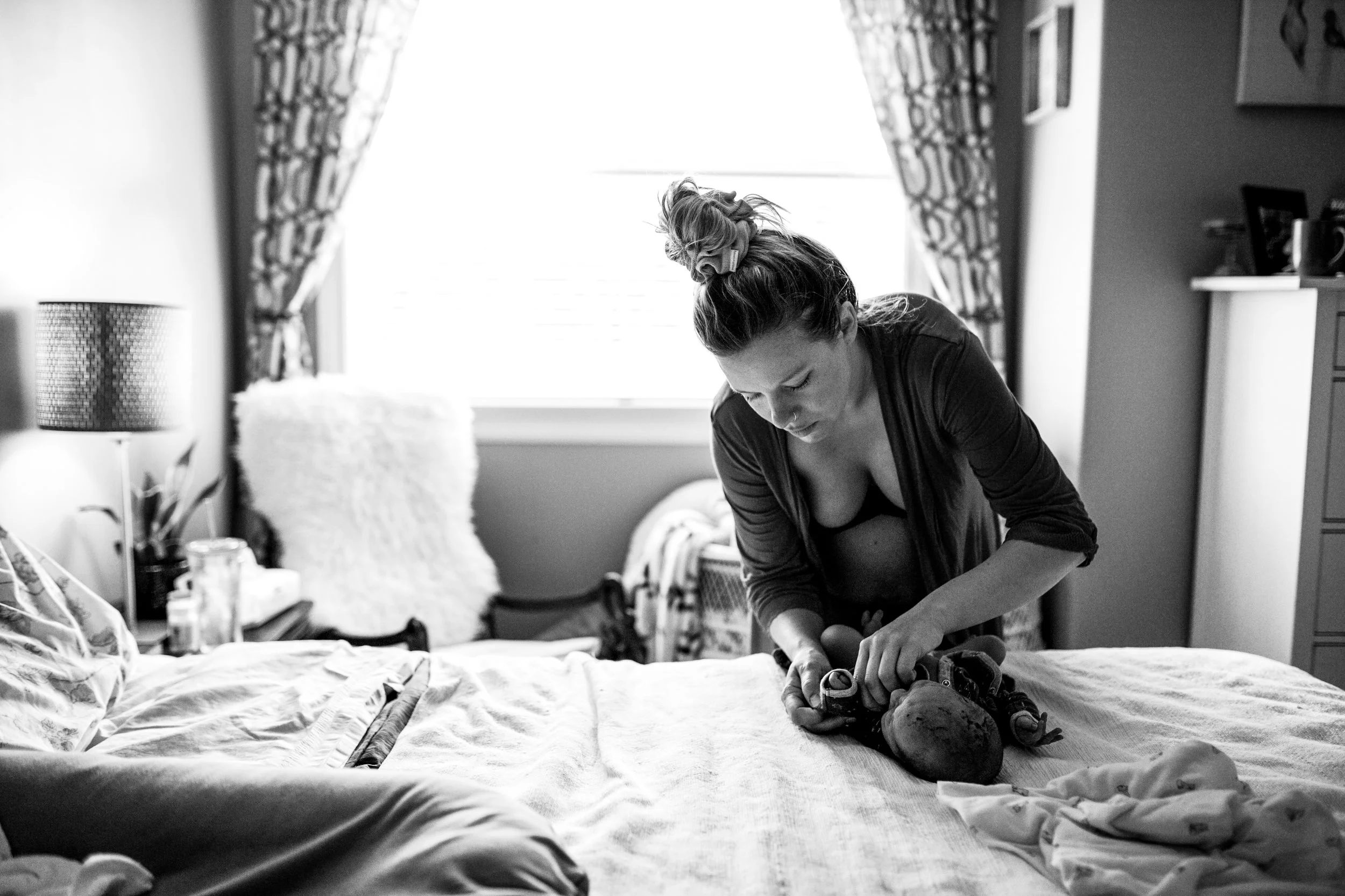 woman-dressing-her-newborn-on-bed.jpg
