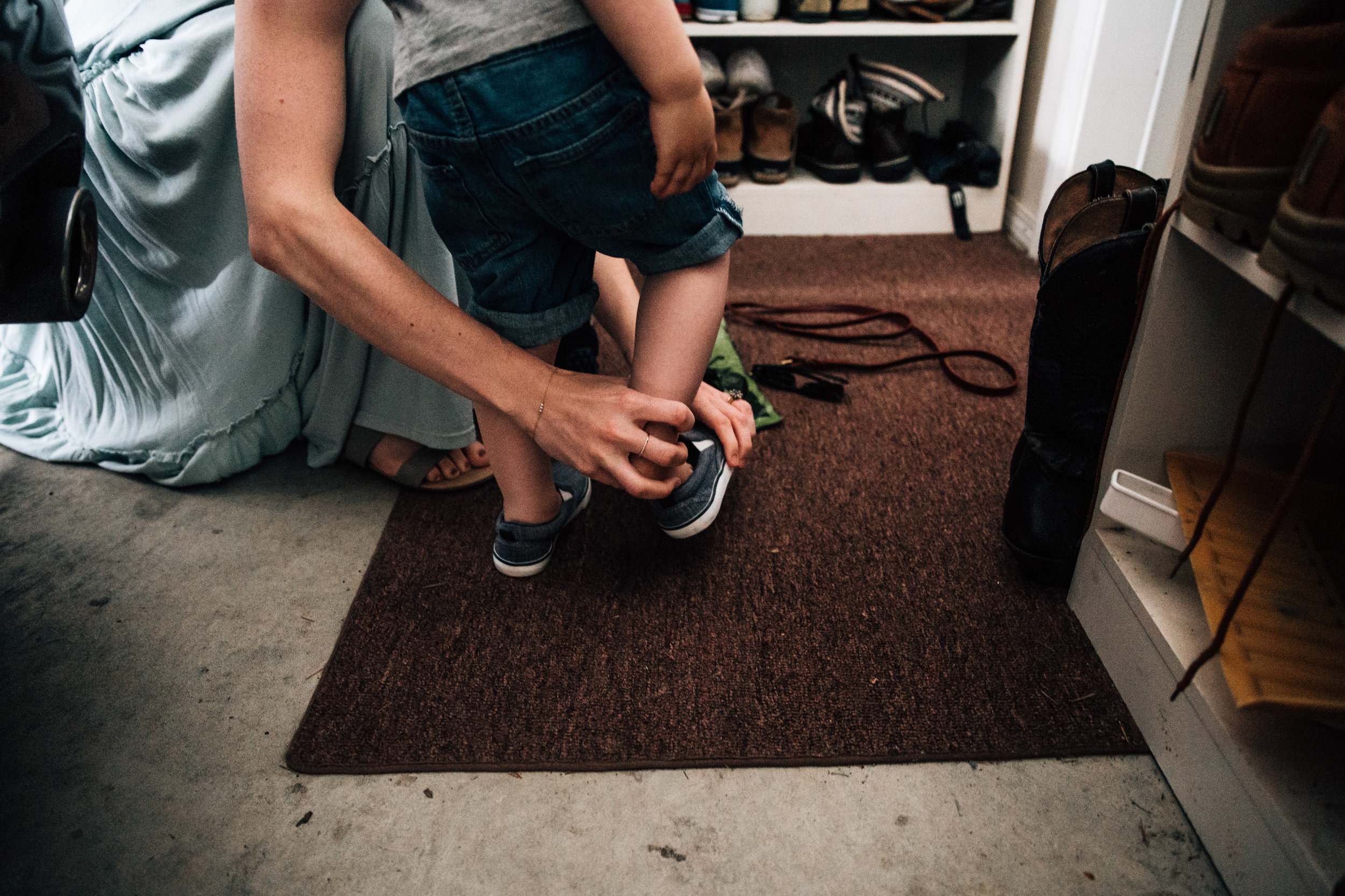 mom putting shoes on toddler boy in garage