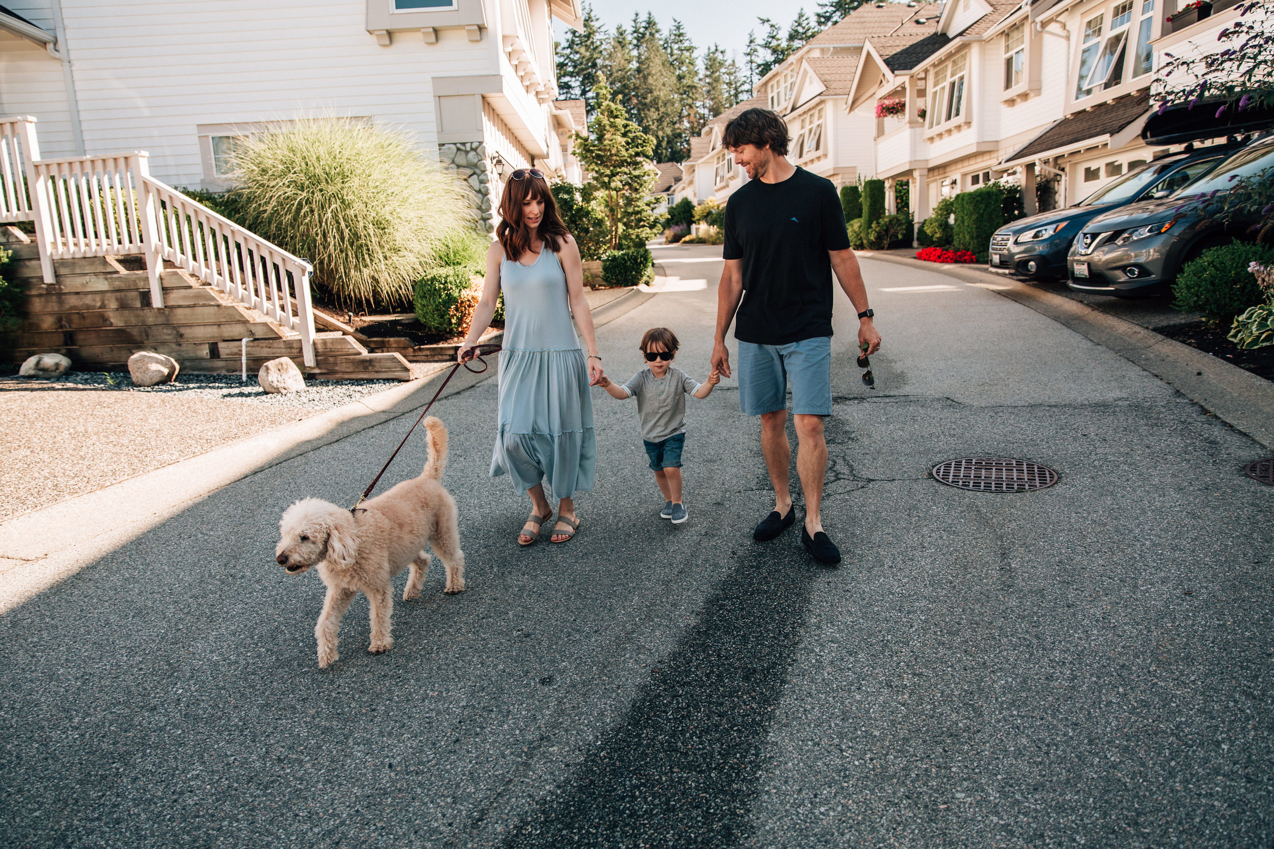 family of three walking down the road with their dog