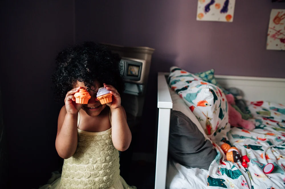 little girl holding cupcakes up to her eyes