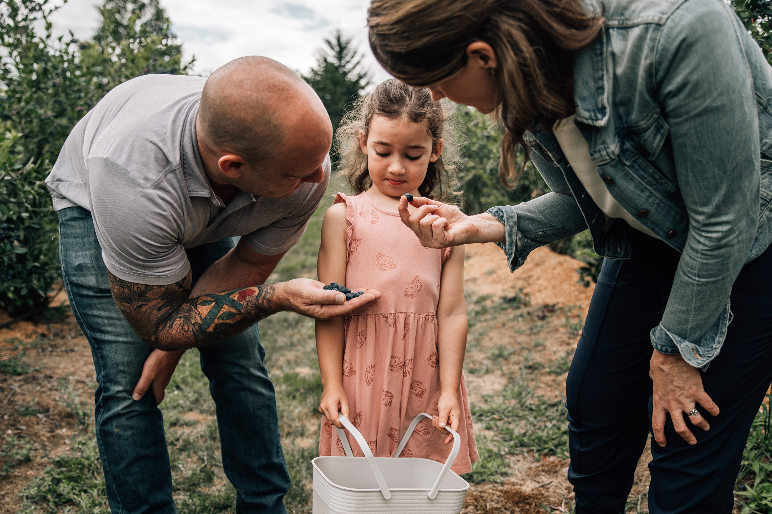 parents offering child blueberries to eat