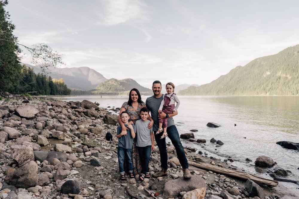 calgary family of five portrait on the rocky beach along the water with mountains in the background