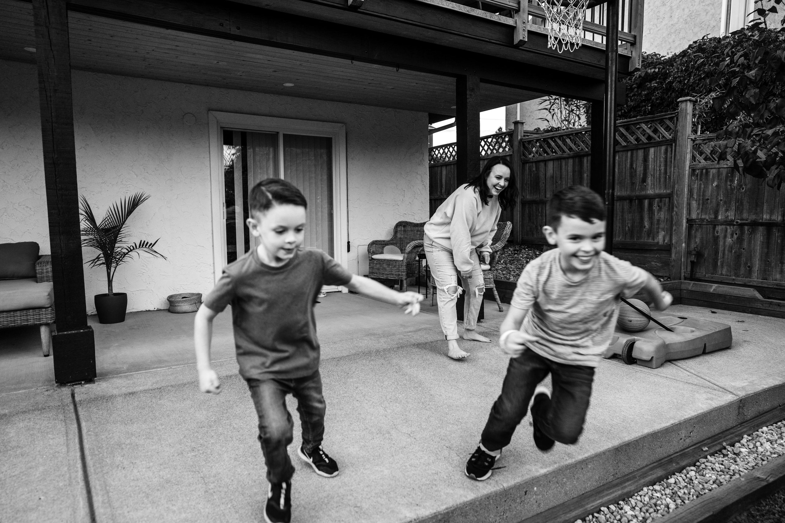 two boys running away from mom while playing basketball