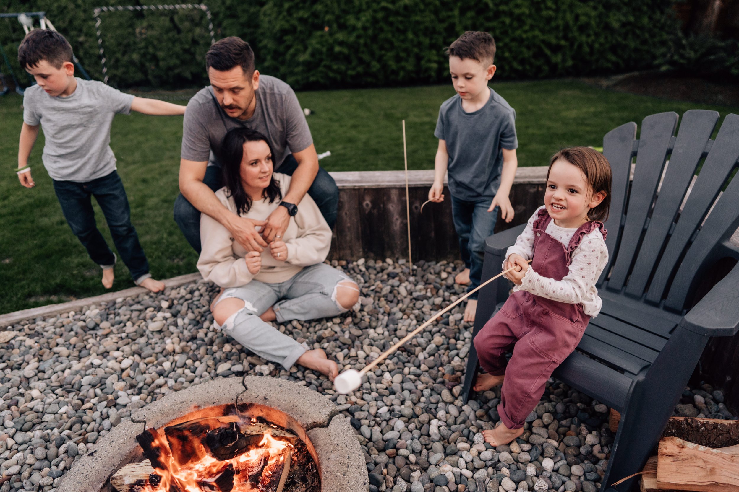 adventurous family roasting marshmallows around small fire in yard