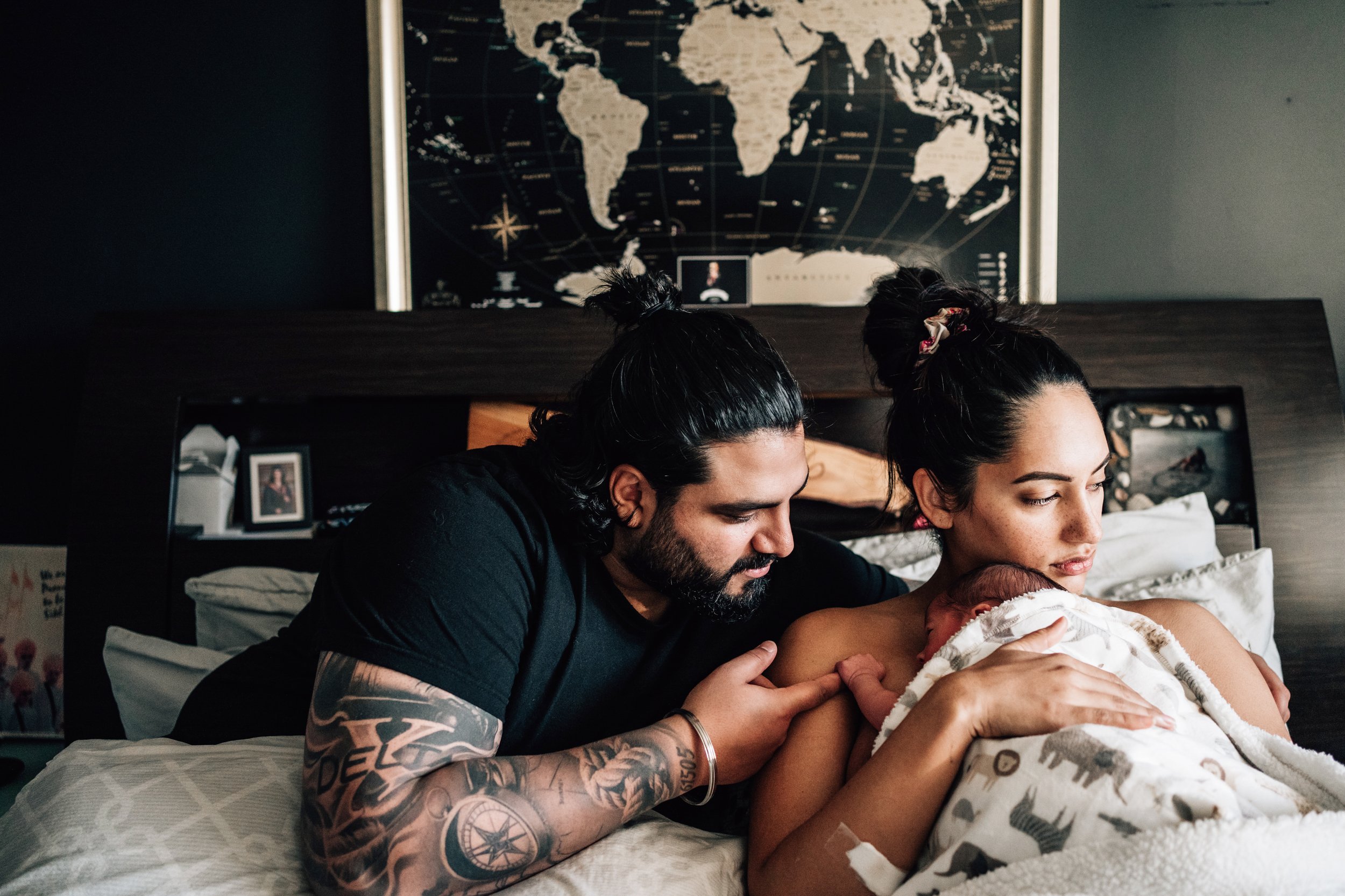 calgary parents during newborn photoshoot on bed with tattoos