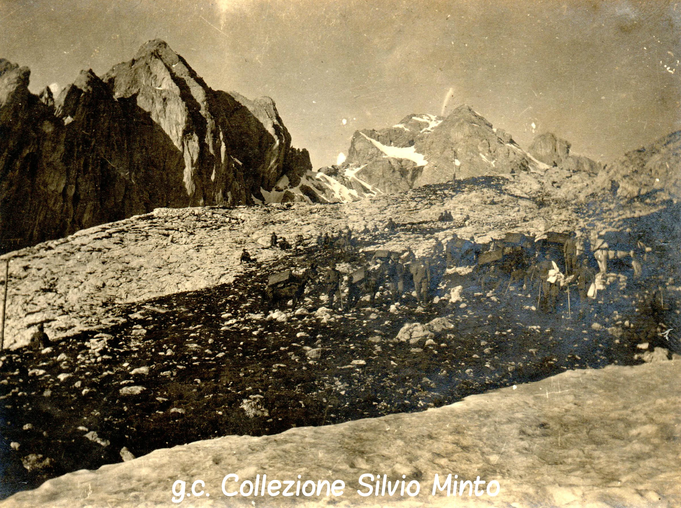 Fotografia ripresa nelle Buse Malacarne, ai piedi della Cima di Ceremana (a sinistra), verso la Forcella Valcigolera (oltre la quale si scende verso San Martino di Castrozza, lungo la Val Bonetta). Sullo sfondo si vede il Colbricon Occidentale (ricostruzione storico-fotografica di Mario Colombo).