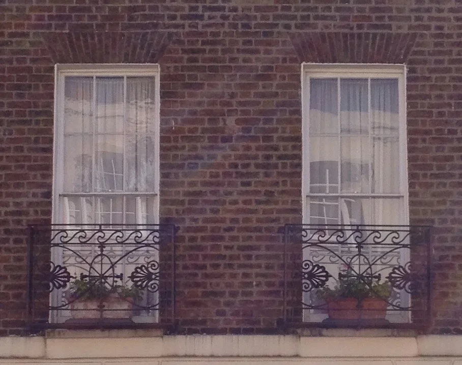 Balconies with wave motif and antheniums. The windows have brick flat arches over a Georgian sash