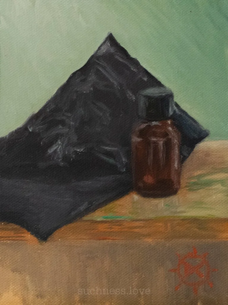 A small brown glass bottle and a black plastic bag on a wooden surface with a plain green background.