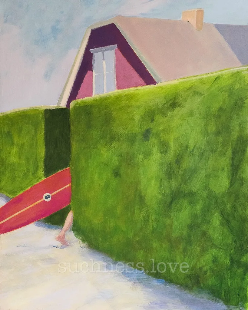 A person walking with only legs visible, carrying a surfboard, behind a green hedge in front of a house with a pink wall and a large window.