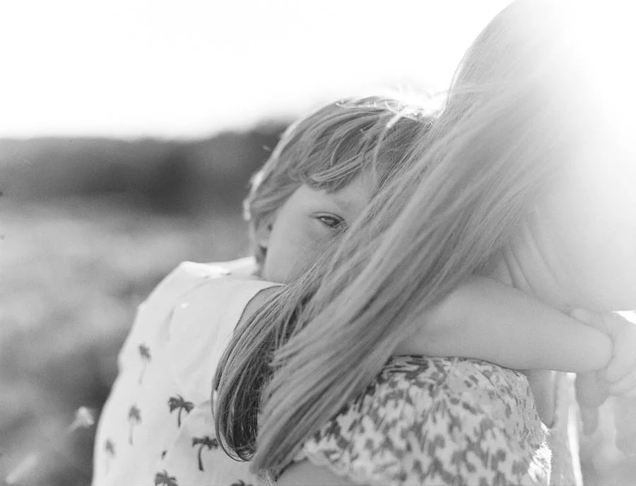 Film photograph of son peeking out from mums hair on a beach in NSW.jpg