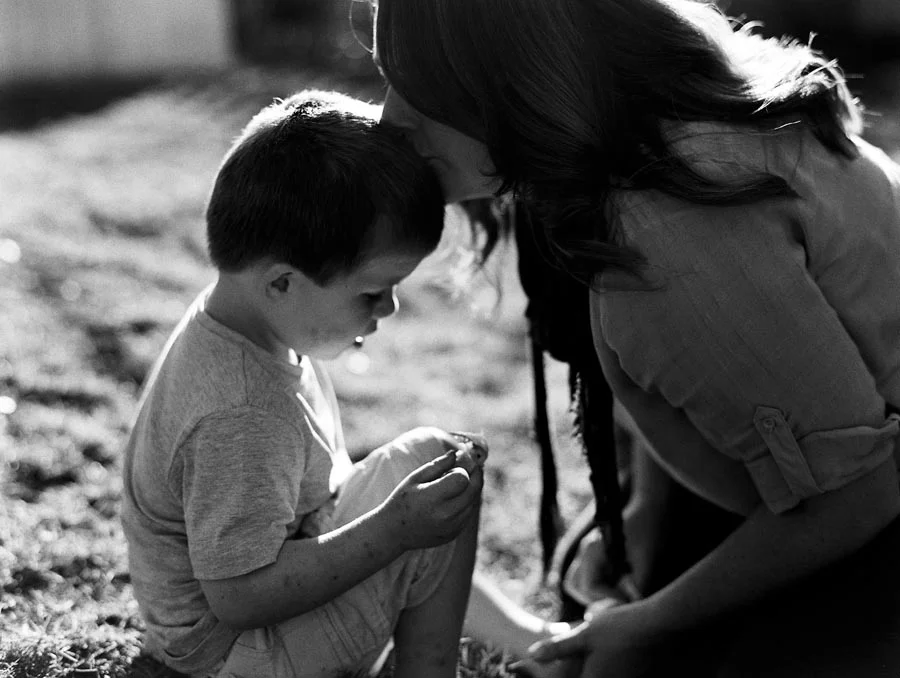 Photograph of a mother kissing her son in their backyard.jpg