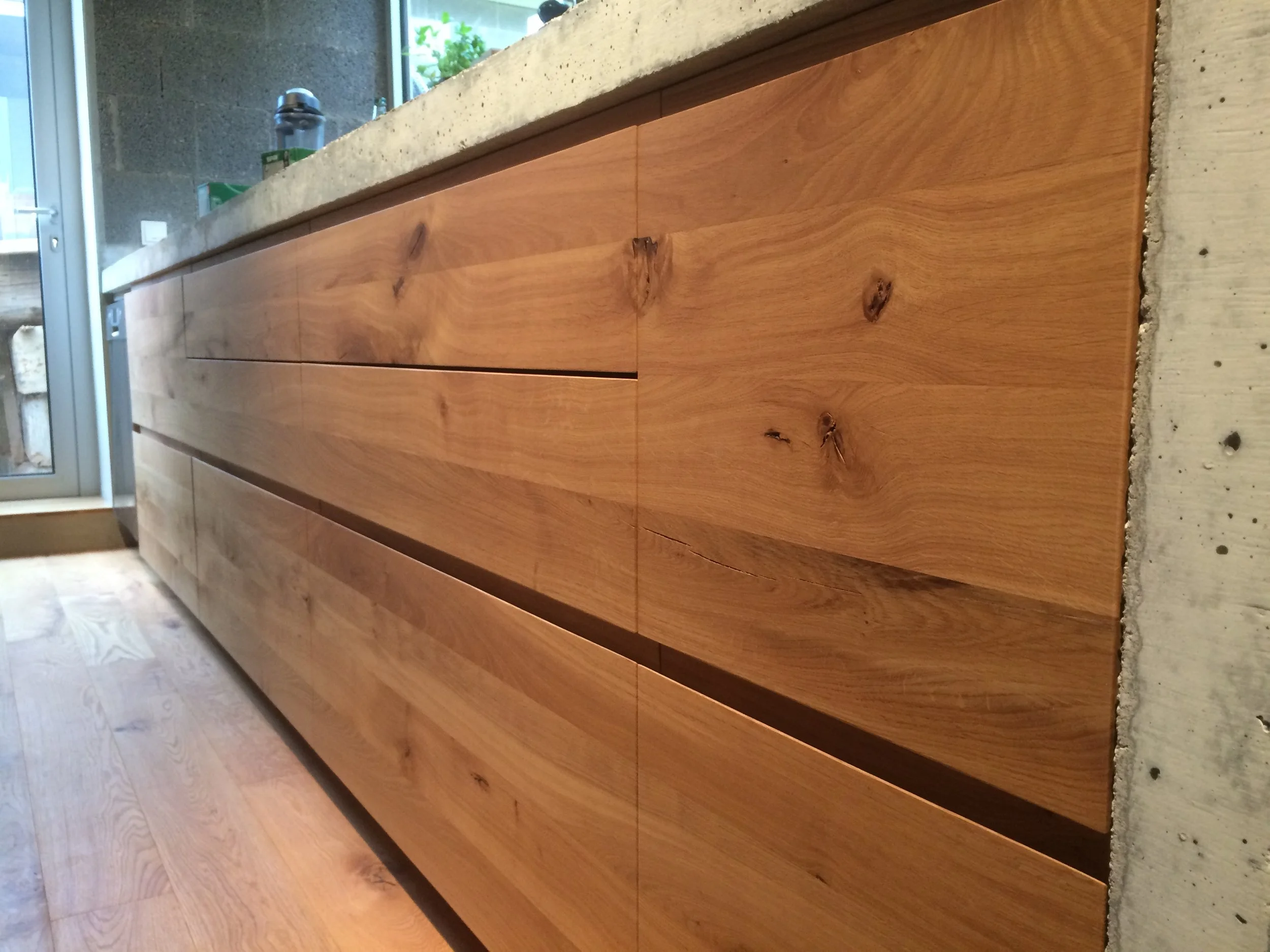 Glatte Küchenfront aus Asteiche mit schlichter Griffausfräsung