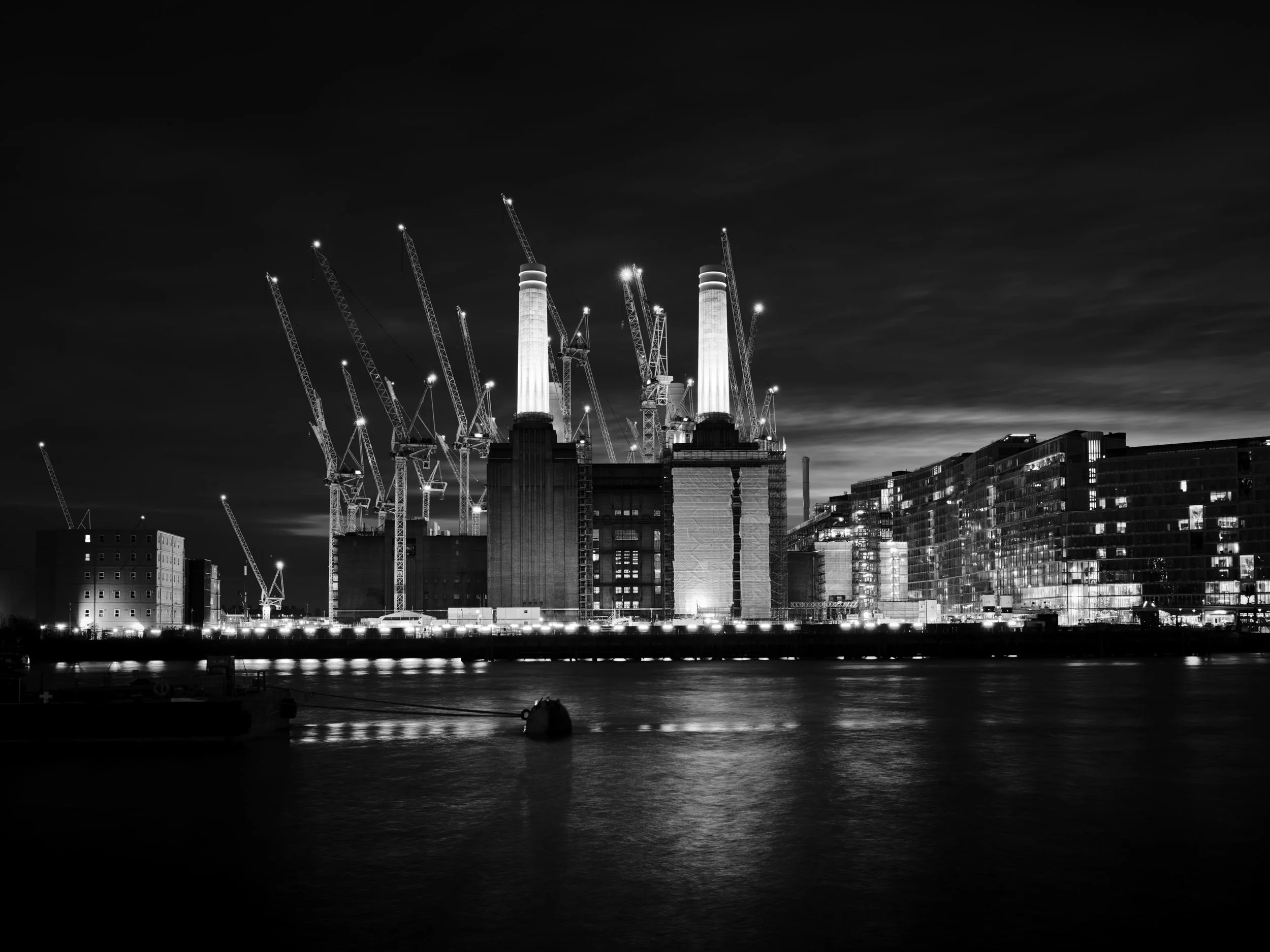 Black and white photo of icebergs floating in water with mountains in the background.