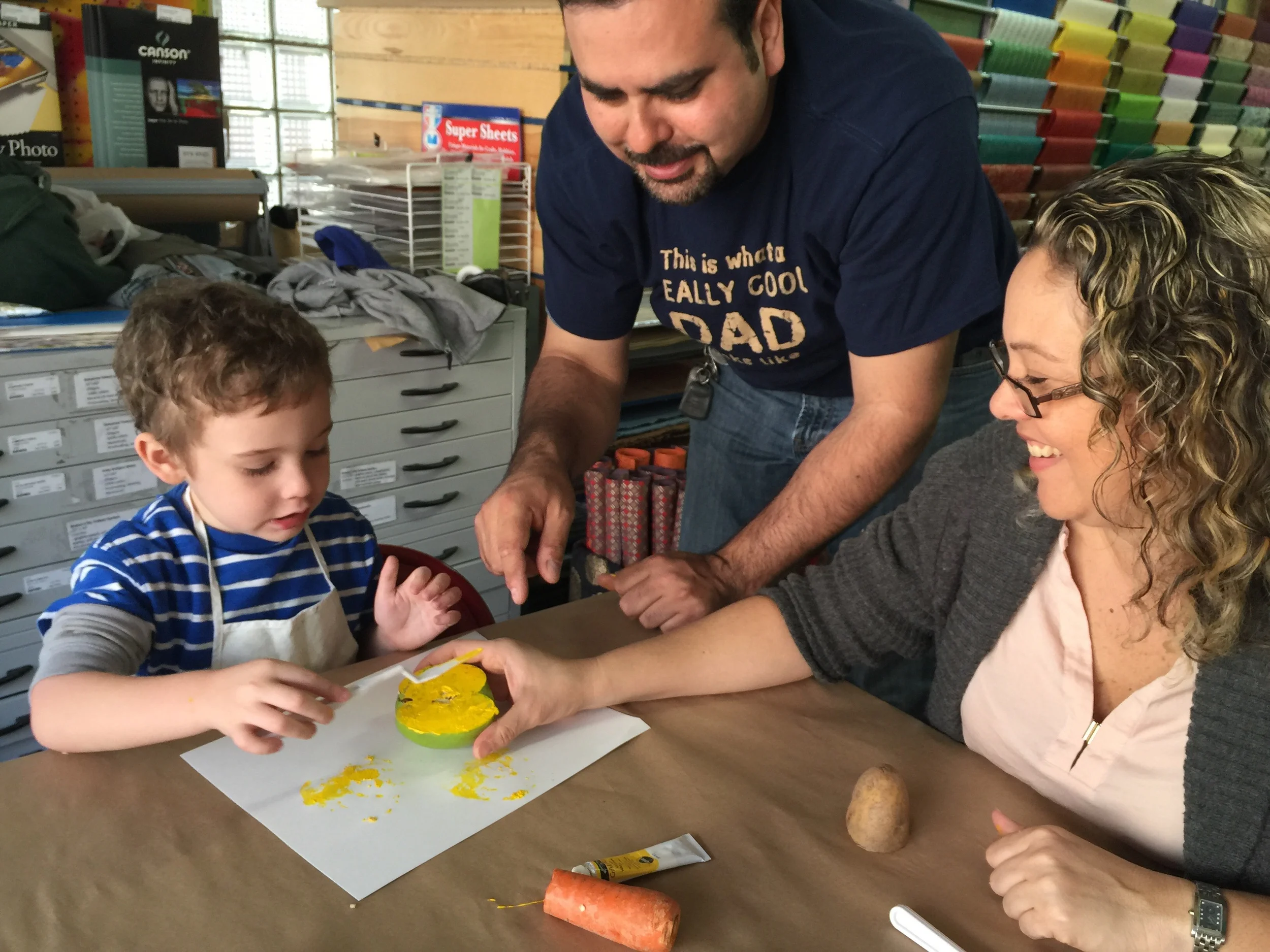 James & his Mommy & Daddy applying "primary yellow" to his Apple for his veggie print! All hands on deck here! We super ❤️ this!!!
