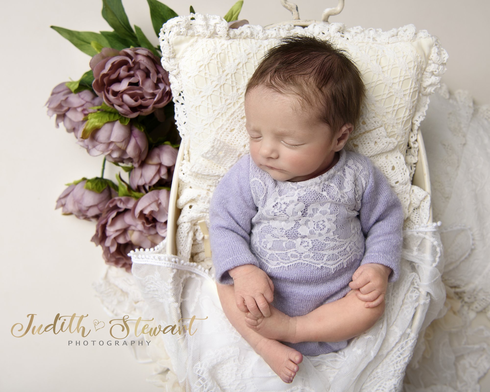 Newborn baby girl in lilac with creams. 