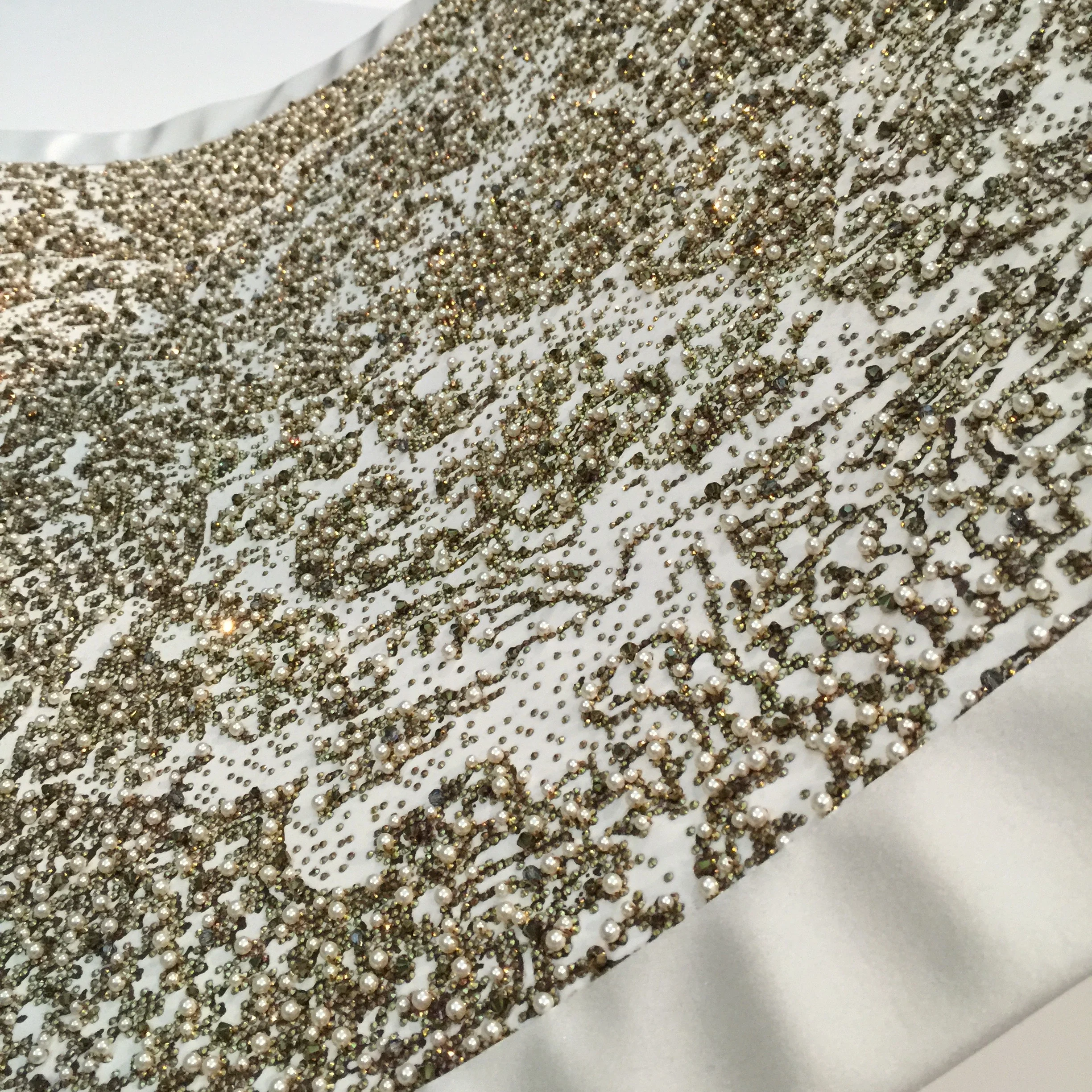 The ornamented train was initially sketched by hand, then manipulated on the computer to create the appearance of a "pixelated baroque pattern," then hand-painted with gold metallic pigment, then machine-printed with rhinestones and finally hand-embroidered with pearls and gemstones. It took 450 hours of workmanship to create. 