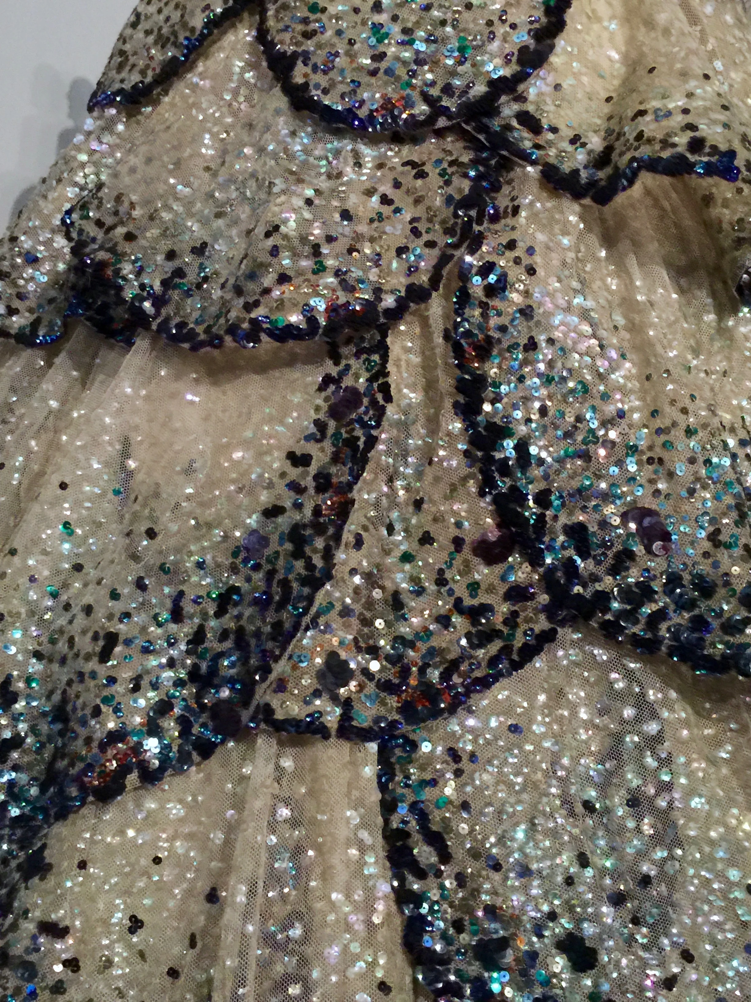 Detail of the hand-embroidered opalescent, blue, green, and orange gelatin sequins.