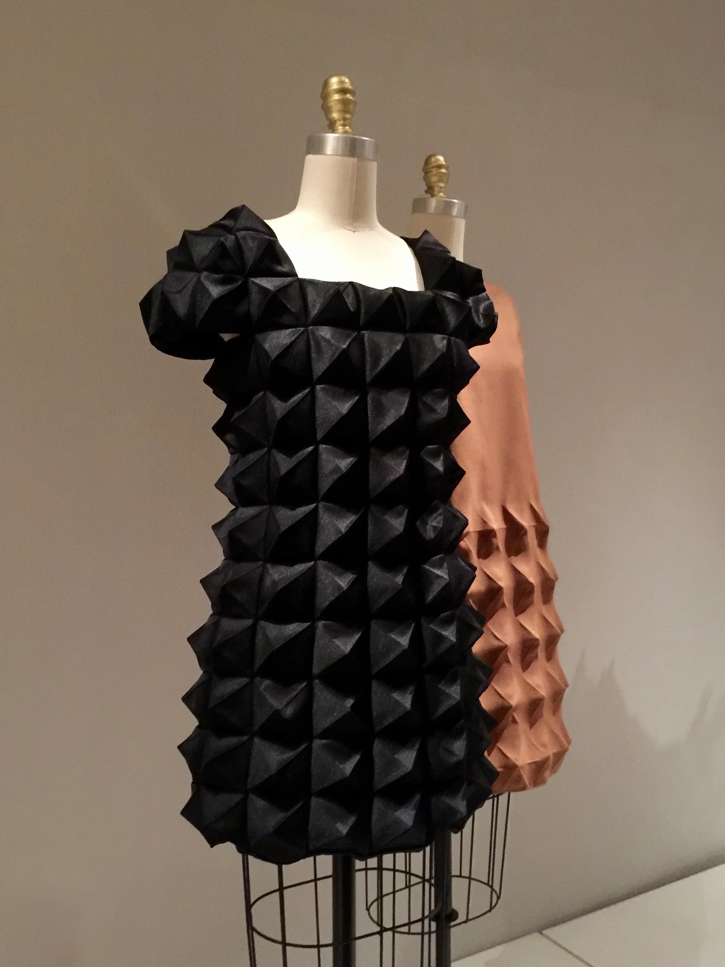 (l) COMME DES GARCONS, Junya Watanabe DRESS, Autumn/Winter 2015-6, pret-a-porter Machine-sewn, heat molded black polyester satin (r) Pierre Cardin DRESS, 1968, haute couture Machine-sewn, heat-molded brown polyester Cardine (Dynel)