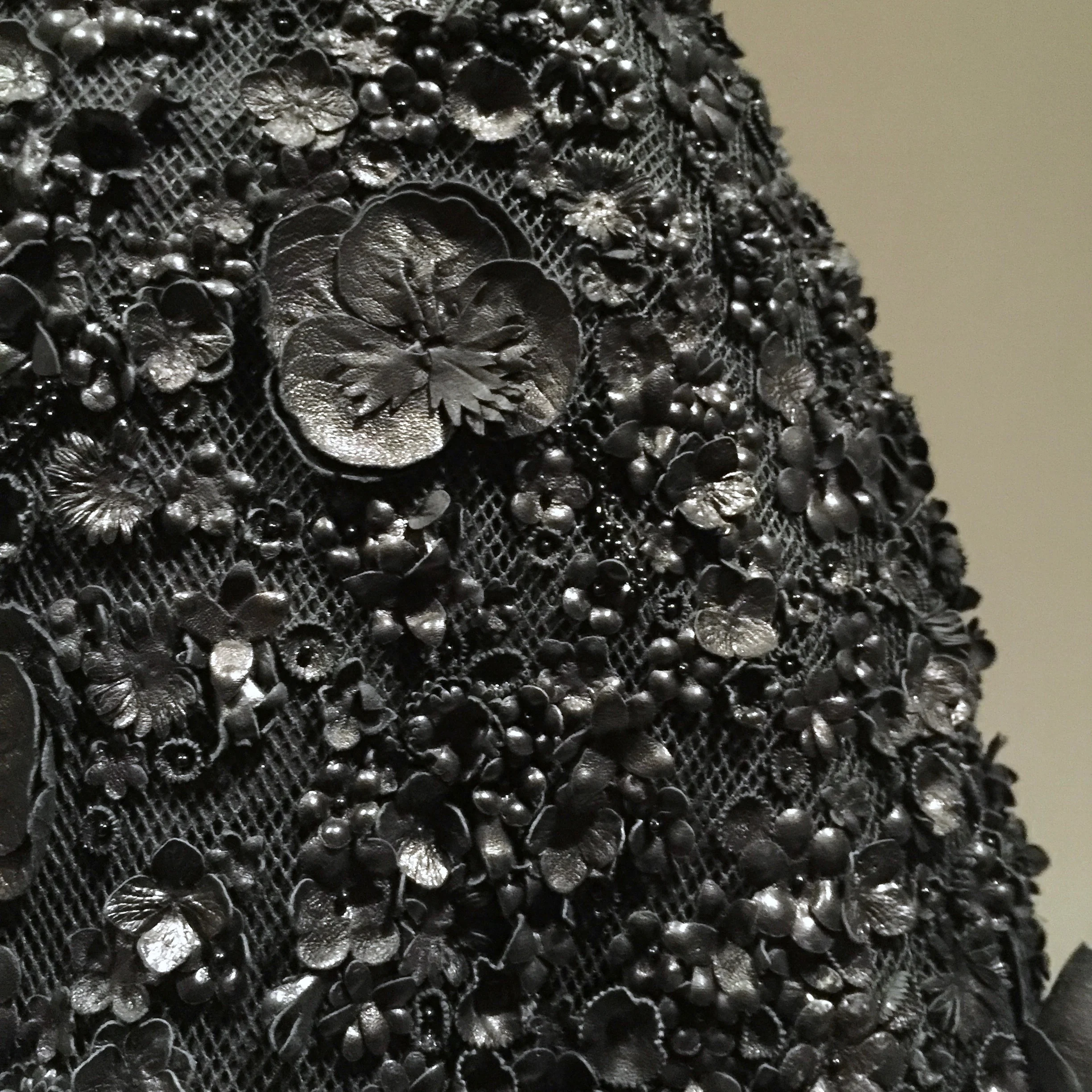 Detail of hand-embroidered leather artificial flowers and black beads