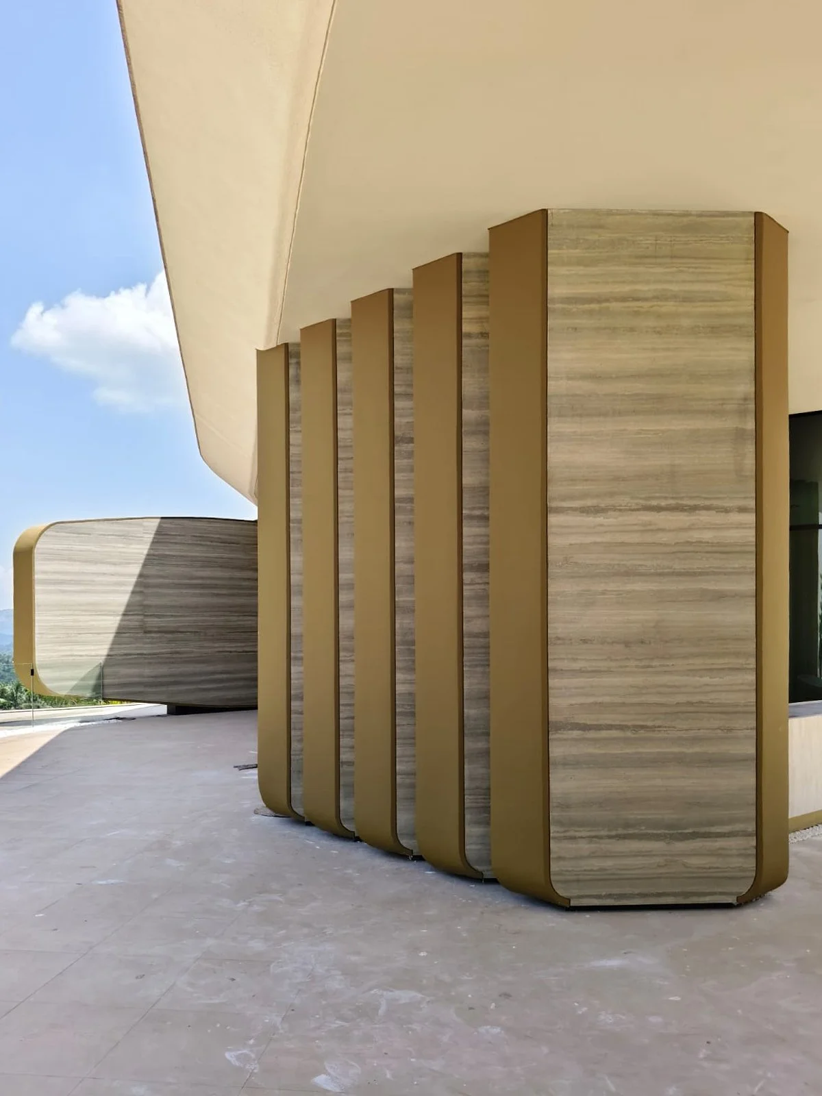 Tulah wellness clinic interior design - golden travertine columns at curved building entrance