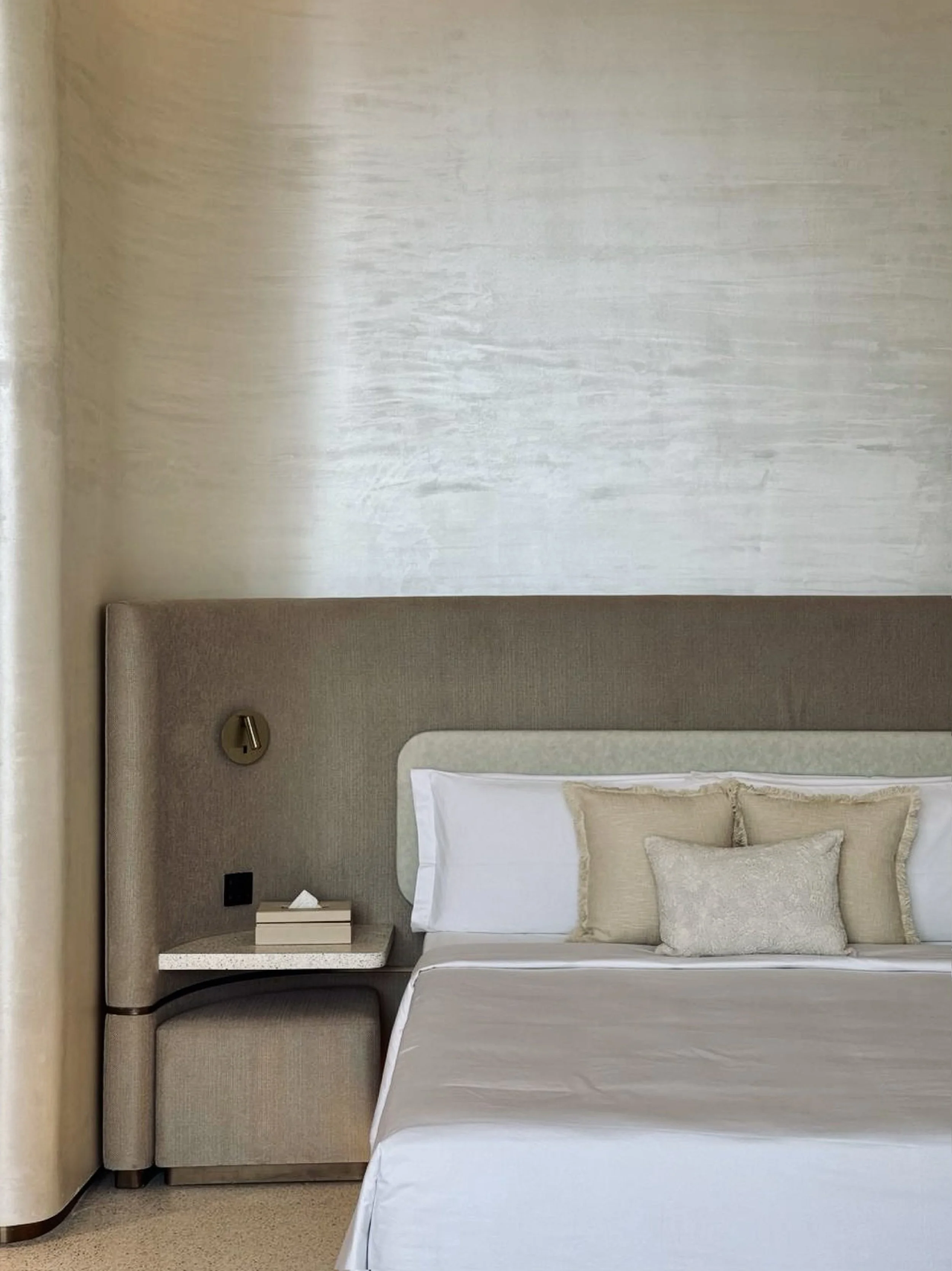 Tulah wellness clinic interior design - minimalist bedroom with stone feature wall and linen bedding