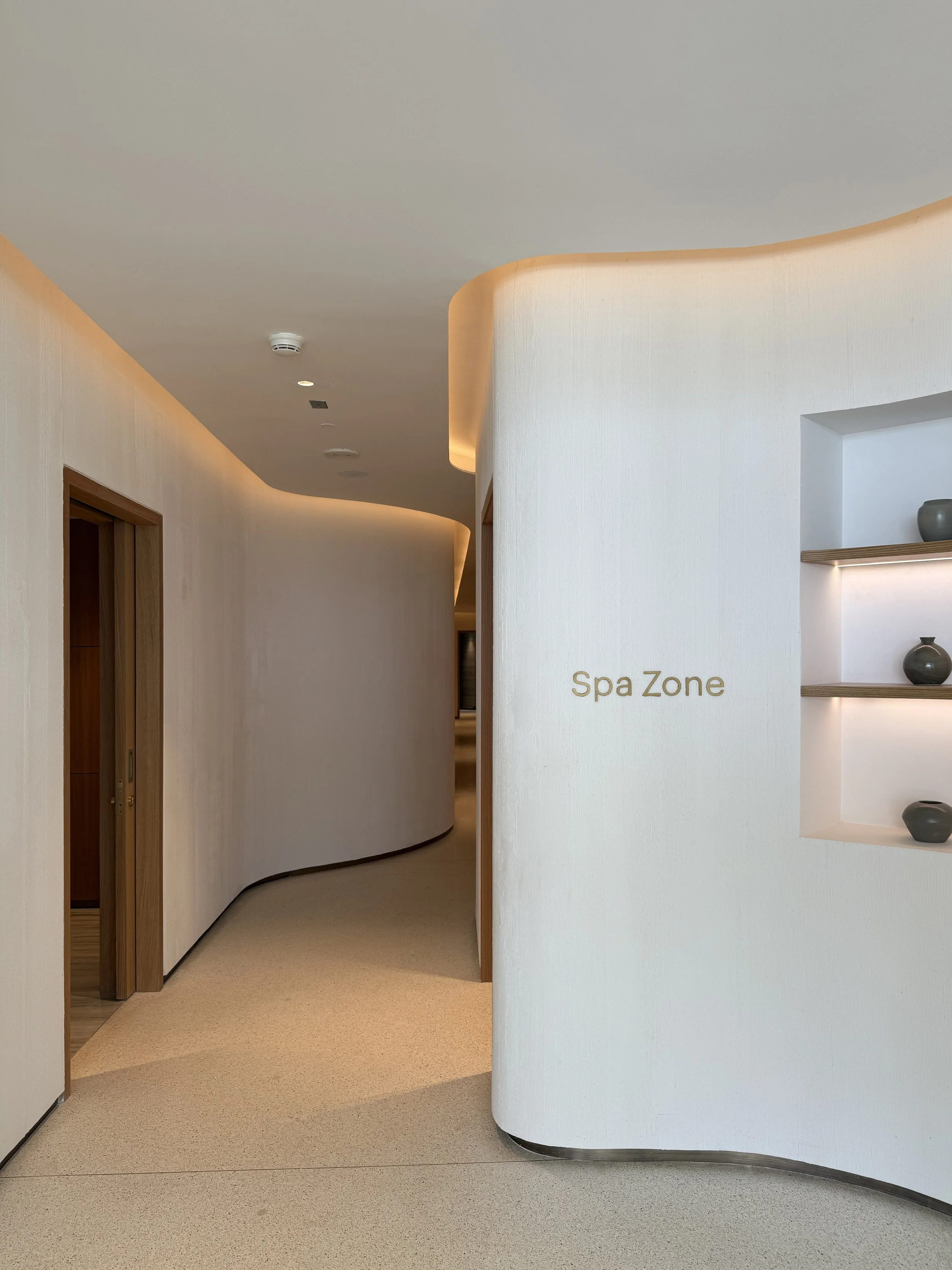 Tulah wellness clinic interior design - spa zone corridor with curved white walls and warm lighting