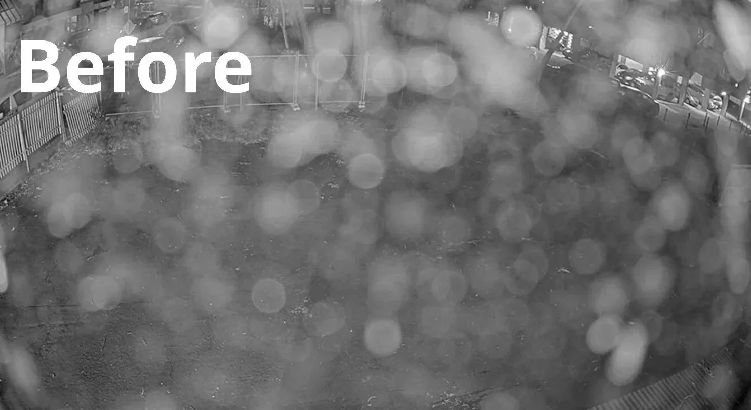 Before cleaning: dark, blurry surveillance camera view of a wet parking lot at night