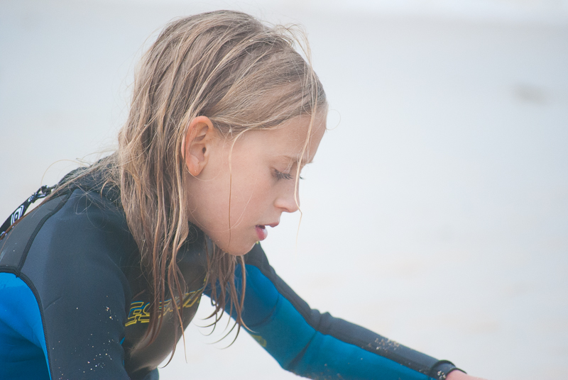 Young surfing girl in wetsuit