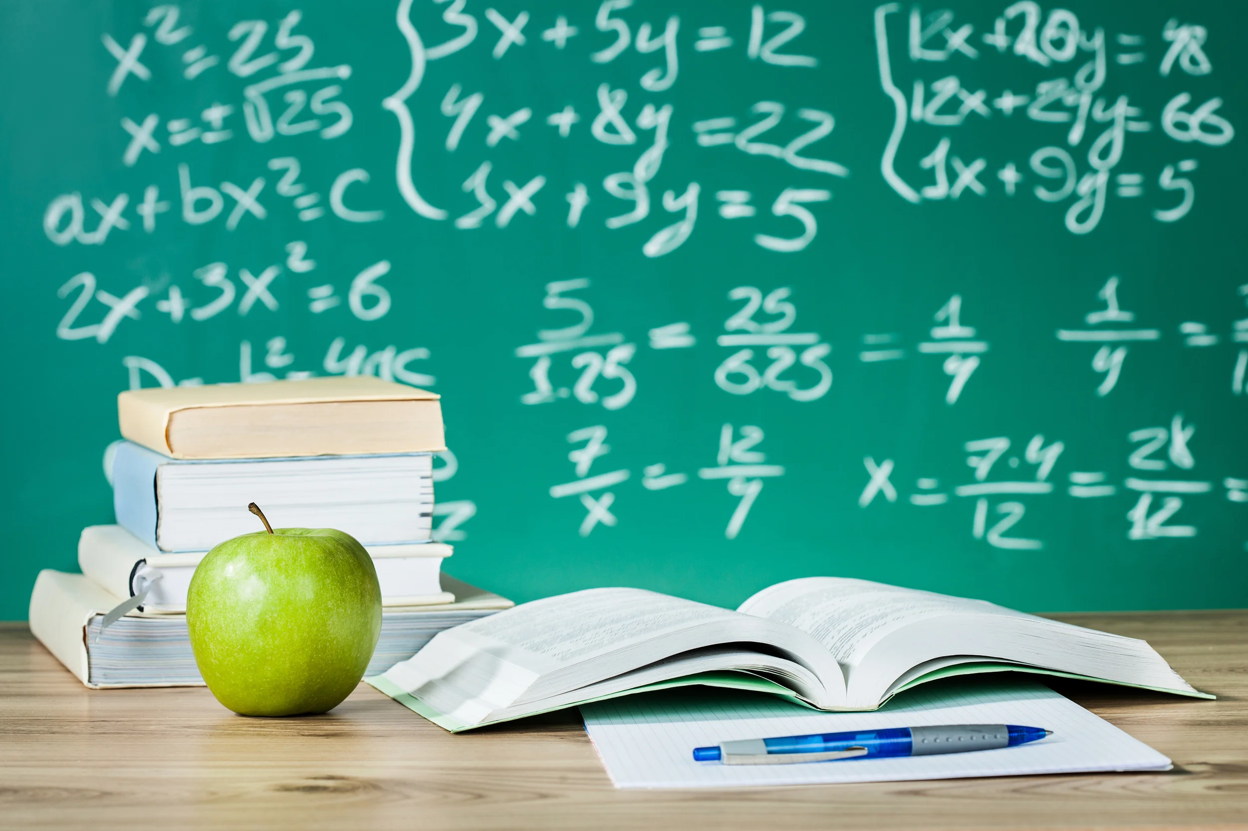 School textbooks on a desk in front of blackboard.jpg