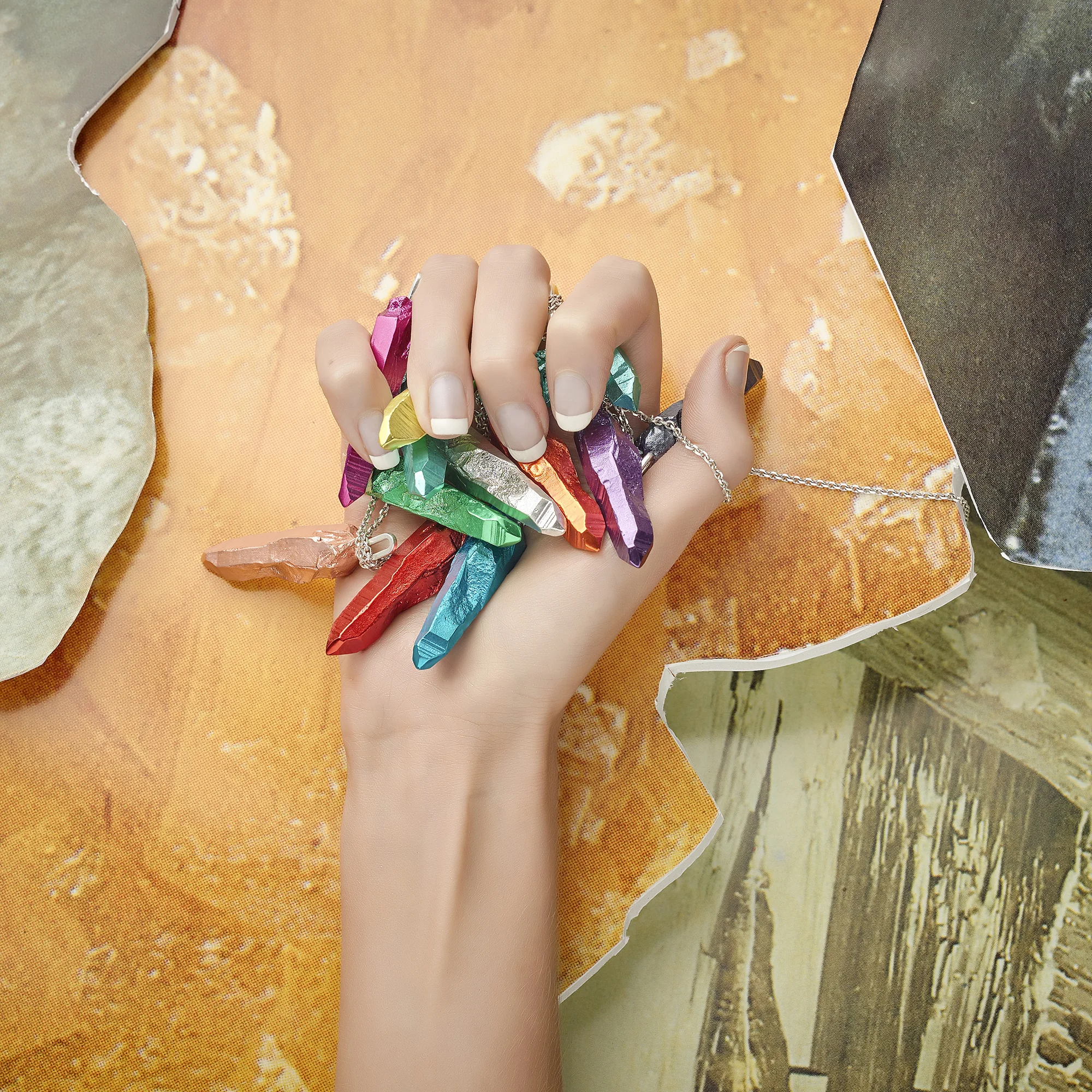 hand model clasping selection of pendant jewellery on colourful vibrant creative still life background, product photography by chris howlett in london