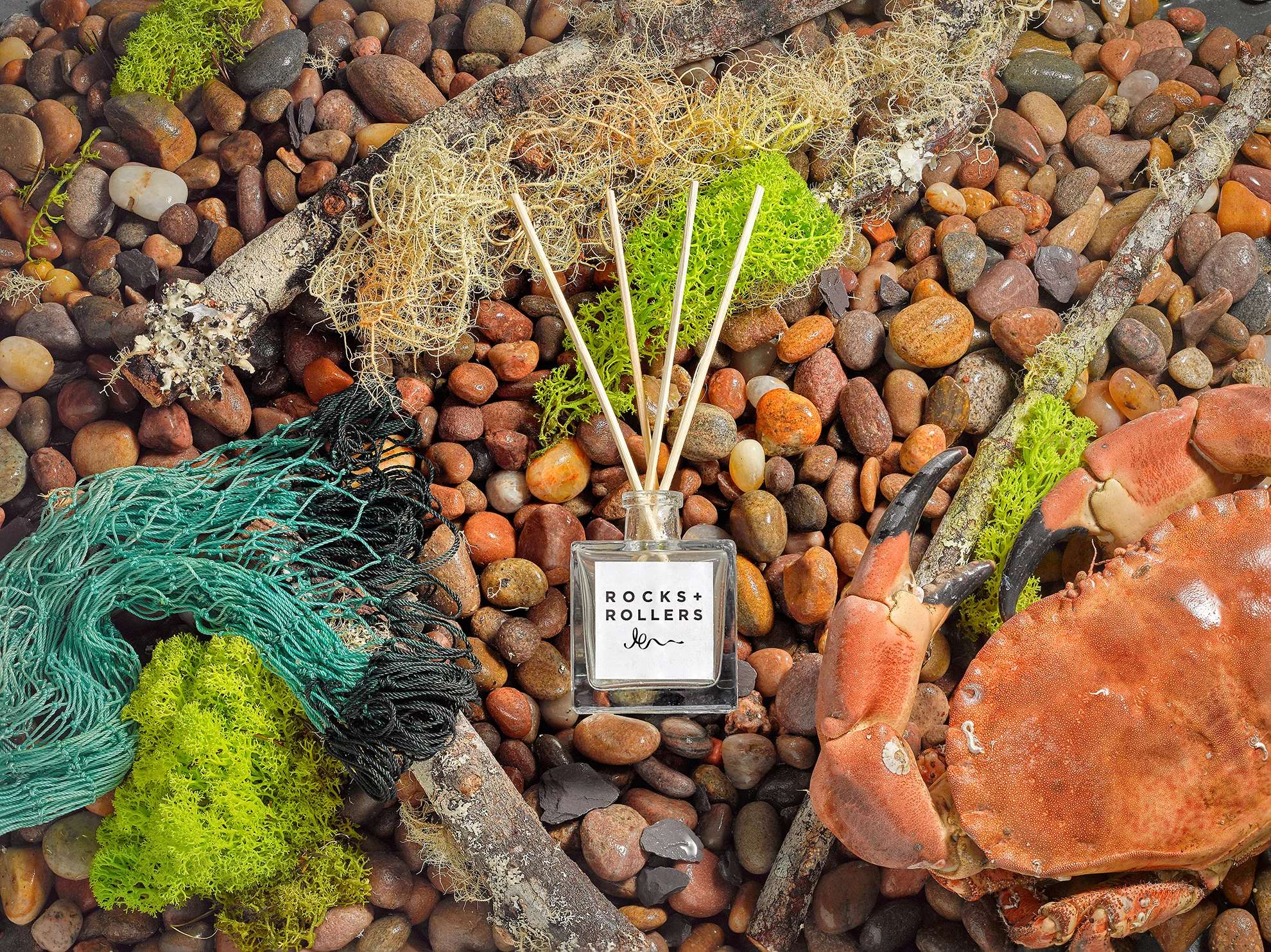 still life product photography from london creative photographer chris howlett. Room fragrance is center image with beach scene, stones sea props an other lifestyle elements