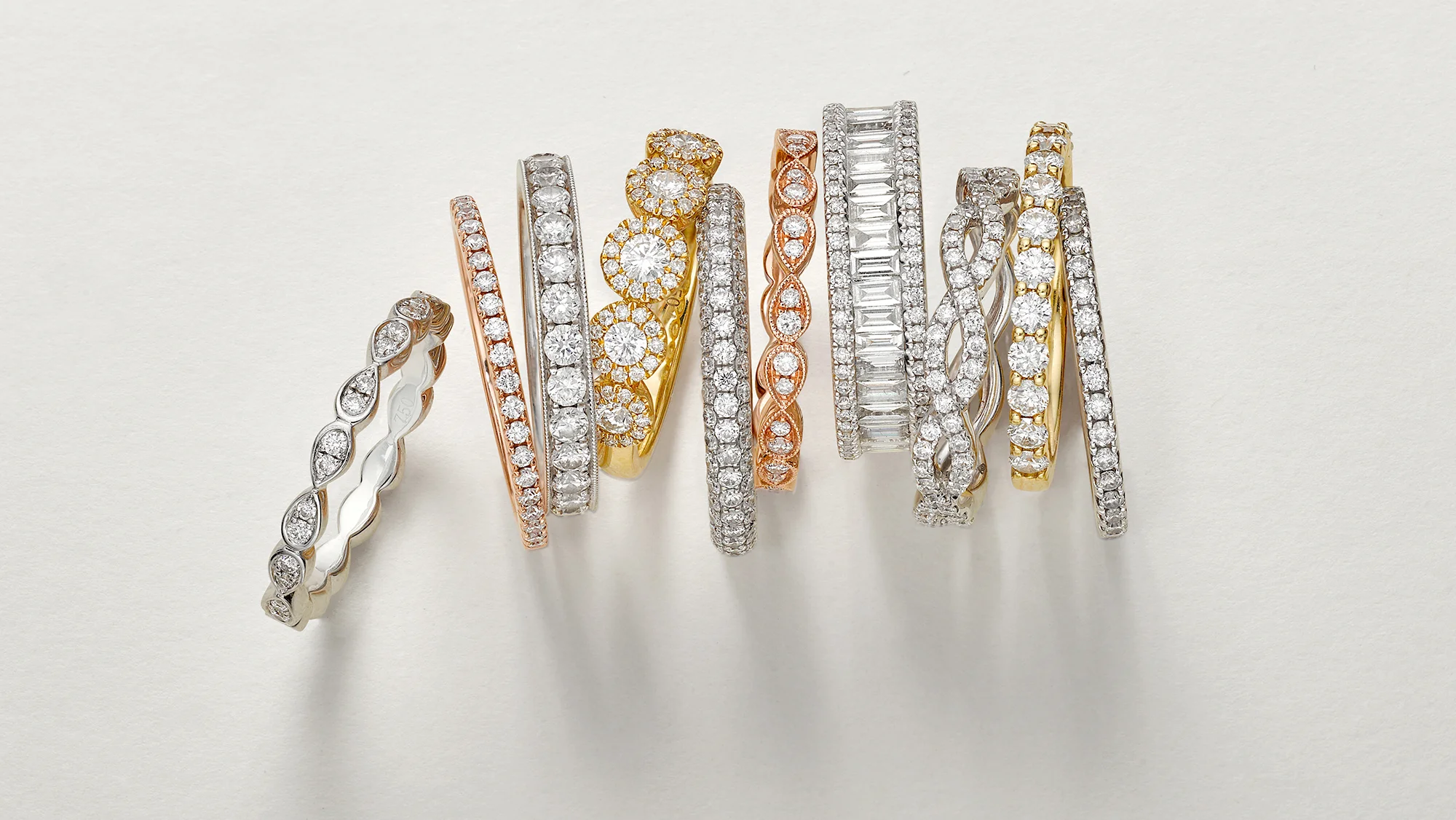 Diamond ring stack with collection of luxury items. Strong shadows against grey neutral background. Creative still life jewellery created by chris howlett photography in London
