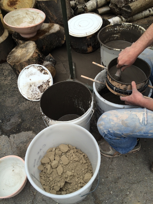 Persuading a suspension of washed ash through an 80 mesh sieve. A bucket of washed, sieved and dried oak ash, ready for use, can be seen in the foreground (just turned out of the biscuit fired bowl, top left, used for drying).