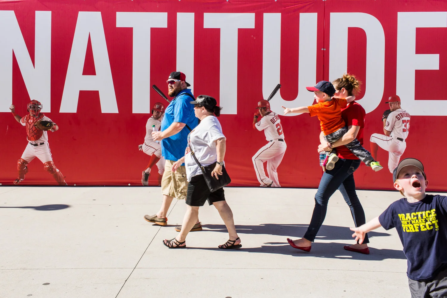 Washington Nationals fans walk past a banner displaying a portion of the Nationals motto, "Nothing but Natitude," in Washington, D.C.