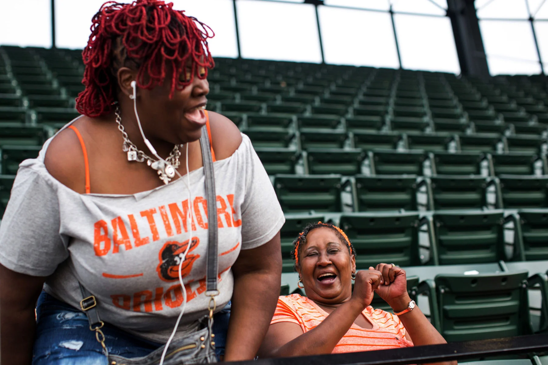 Social worker Joy Aisha Bell, left, laughs with Joann Wilson, who was attending her first baseball game at Camden Yards in Baltimore, MD.