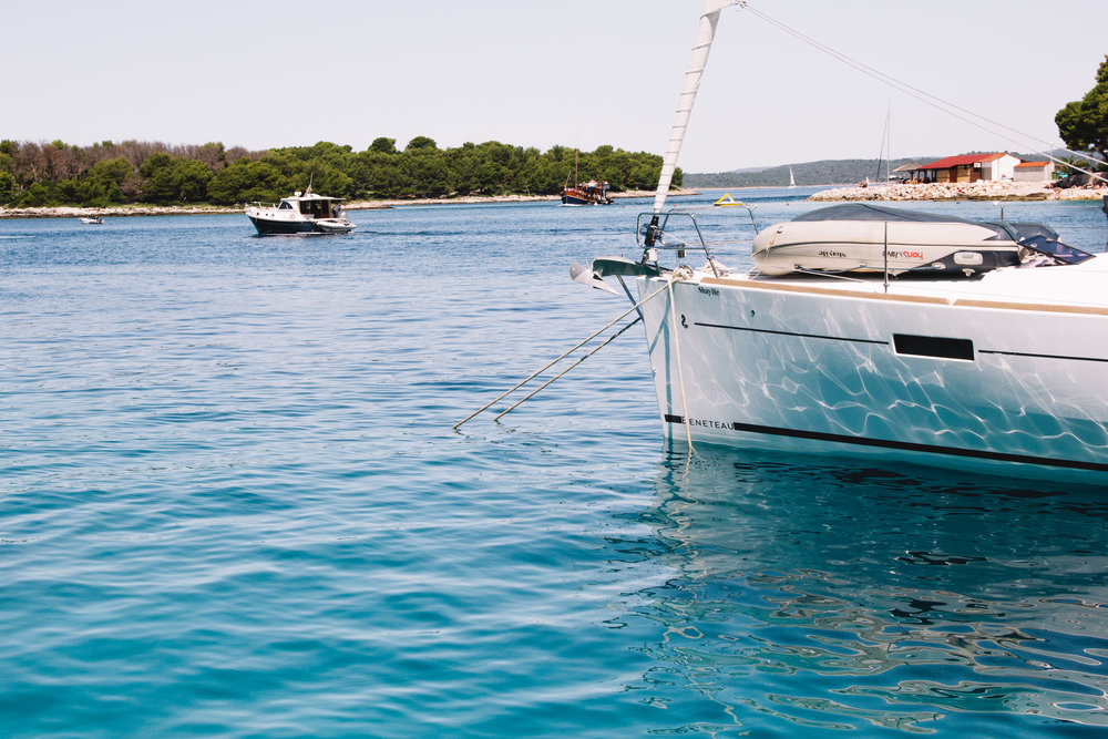 The water reflects on the side of a Beneteau sailboat