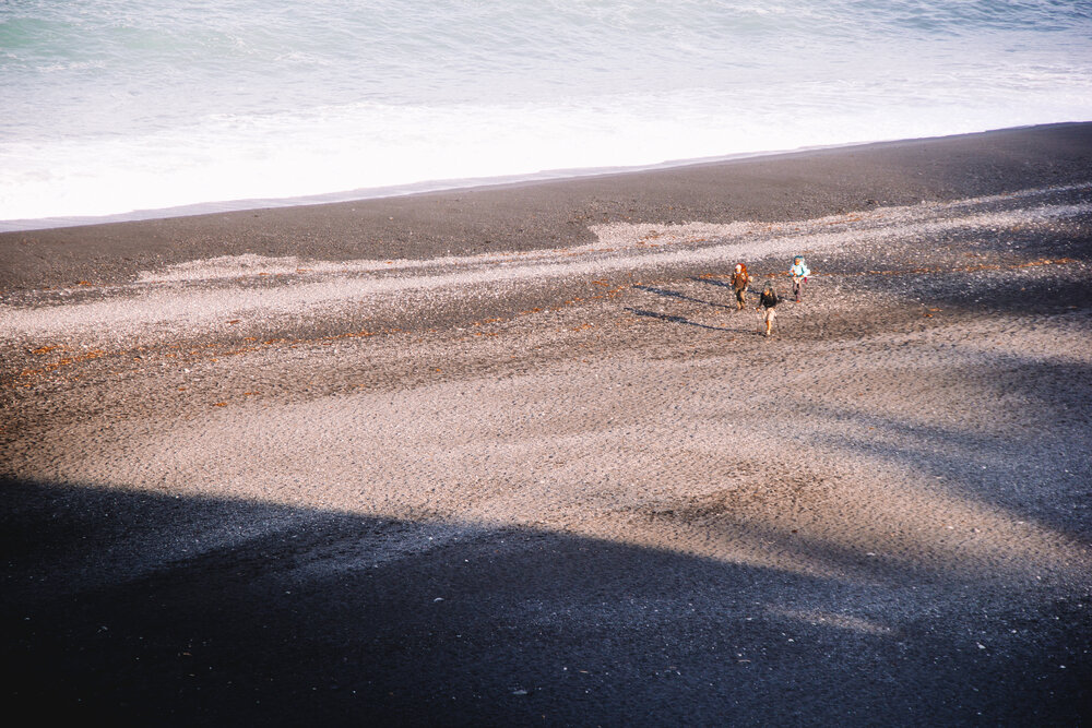 Three hikers on their final approach to Shelter Cove on Black Sands Beach