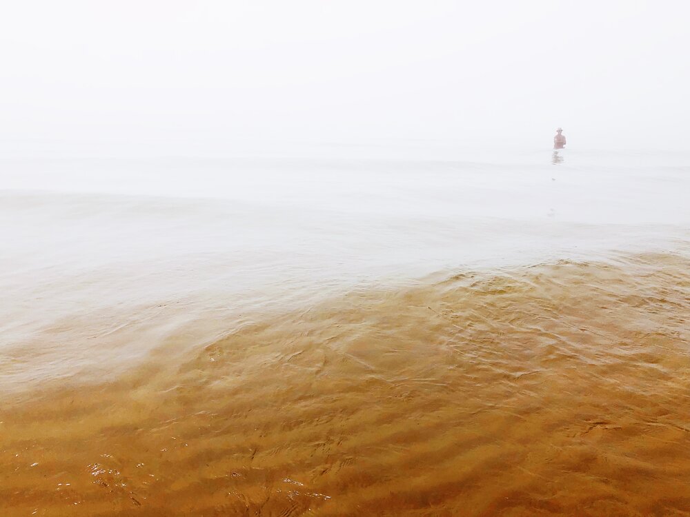 A man wades out into the shallow waters