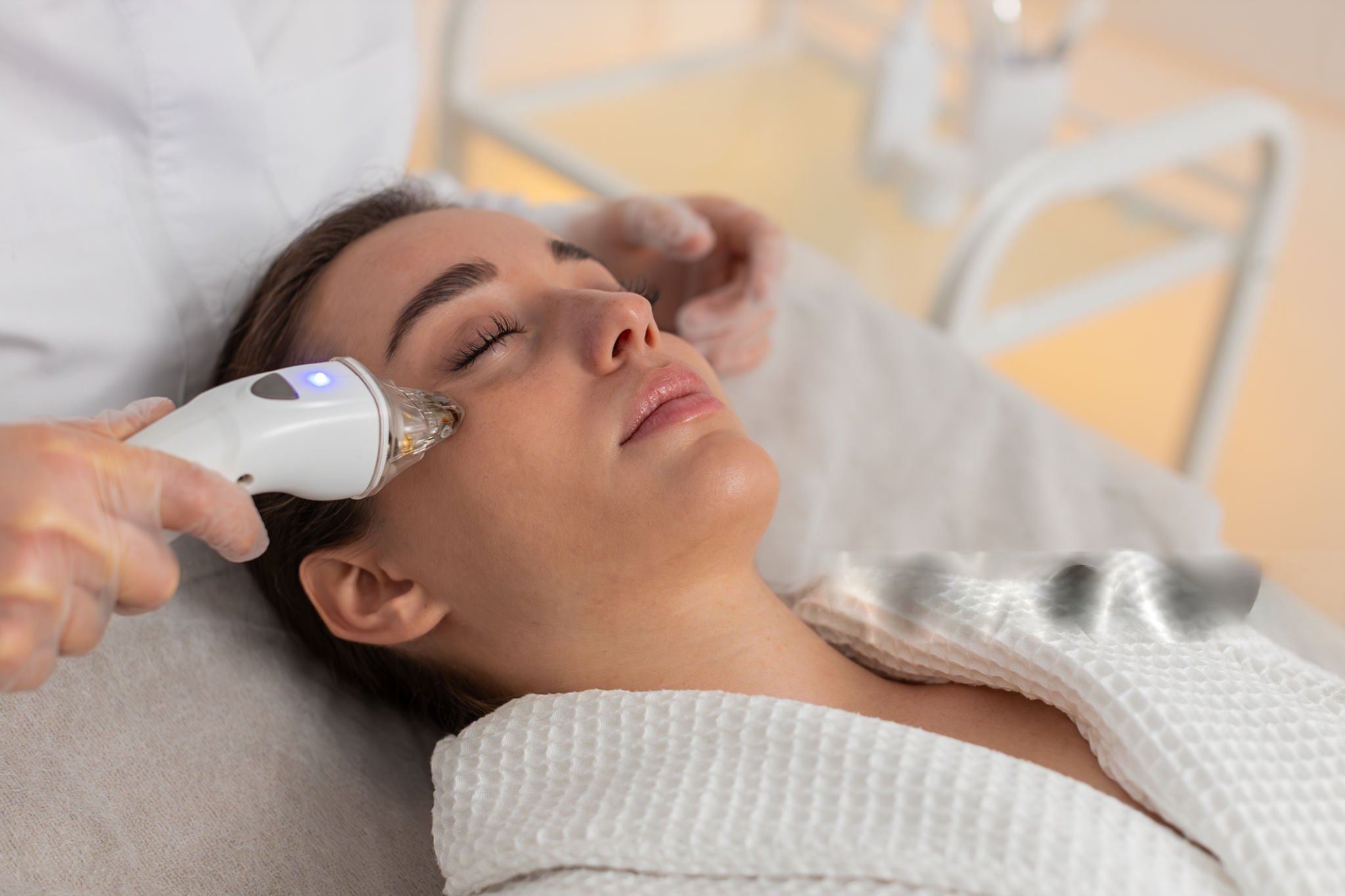 Woman receiving a facial treatment with a handheld device at a spa or medical clinic