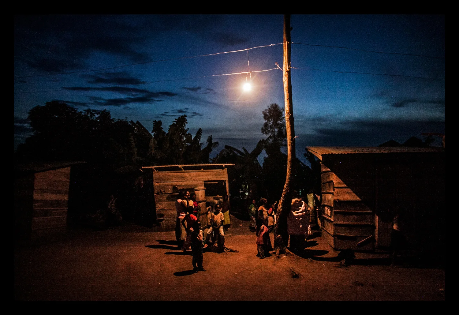 Women and children line up at a grinding mill at dusk
