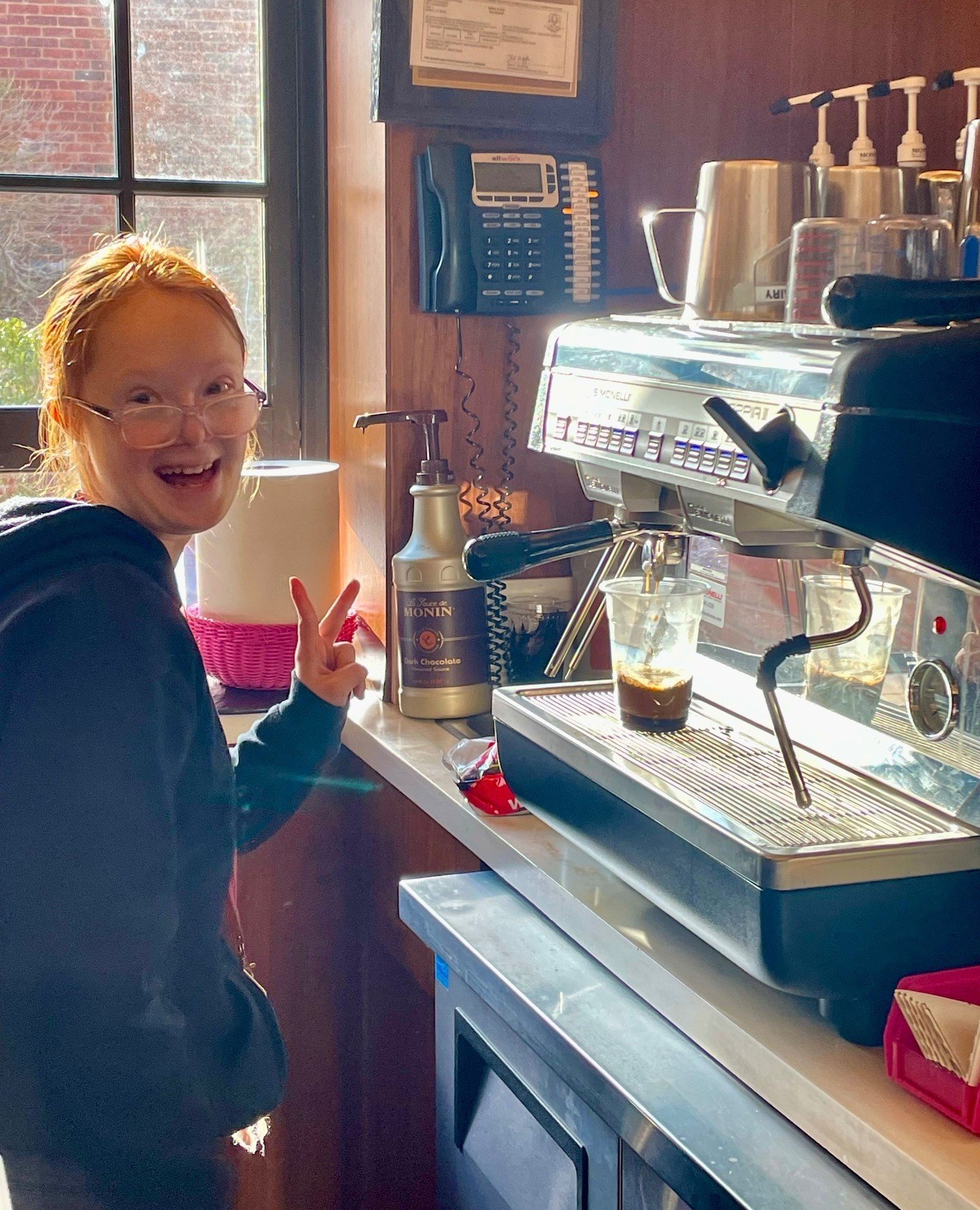 Hey Brooklyn ✌️💖 ⁠Stop in and say hi to us!⁠
.⁠
.⁠
.⁠
.⁠
.⁠
Photo caption: Brooklyn makes coffee in Heads Up Cafe while smiling and giving the peace sign. #SparkleOn #ProspectorTheater #WorkingIsWorking